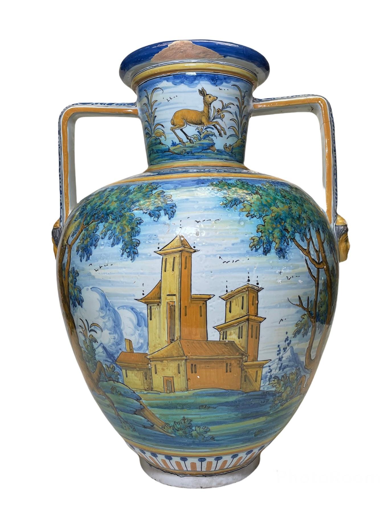 This is a Talavera Majolica large amphora/ urn vase. It is hand painted in the belly with a scene of a country background with a musketeer riding a horse in one side and a country church or monastery in the other one. The neck is hand painted with a