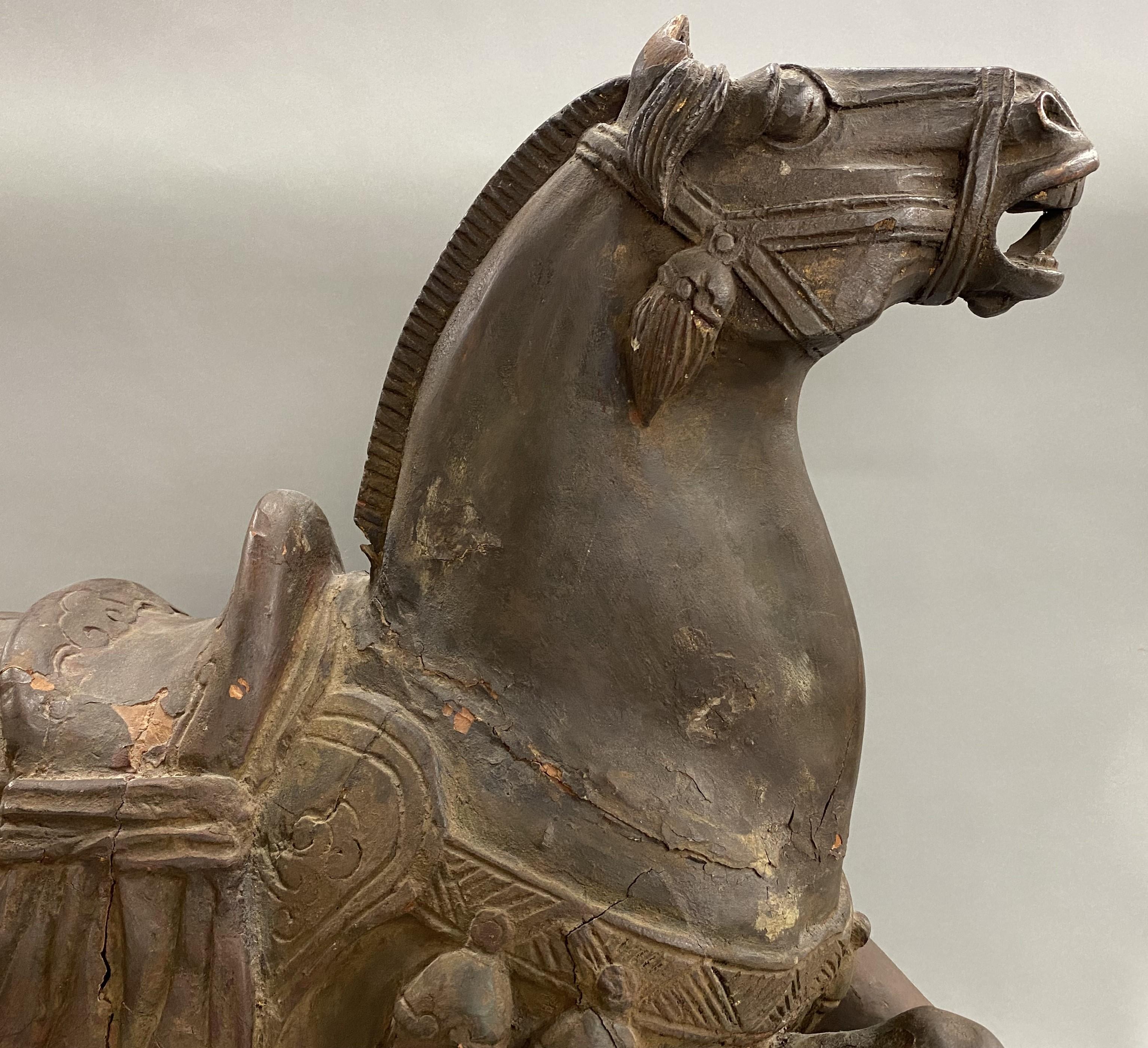 A large nicely detailed carved wooden sculpture of a Tang style horse coming to a halt, on wooden base in its original finish, probably Chinese in origin, dating to the 19th or 20th century. Very good overall condition, with some losses, shrinkage