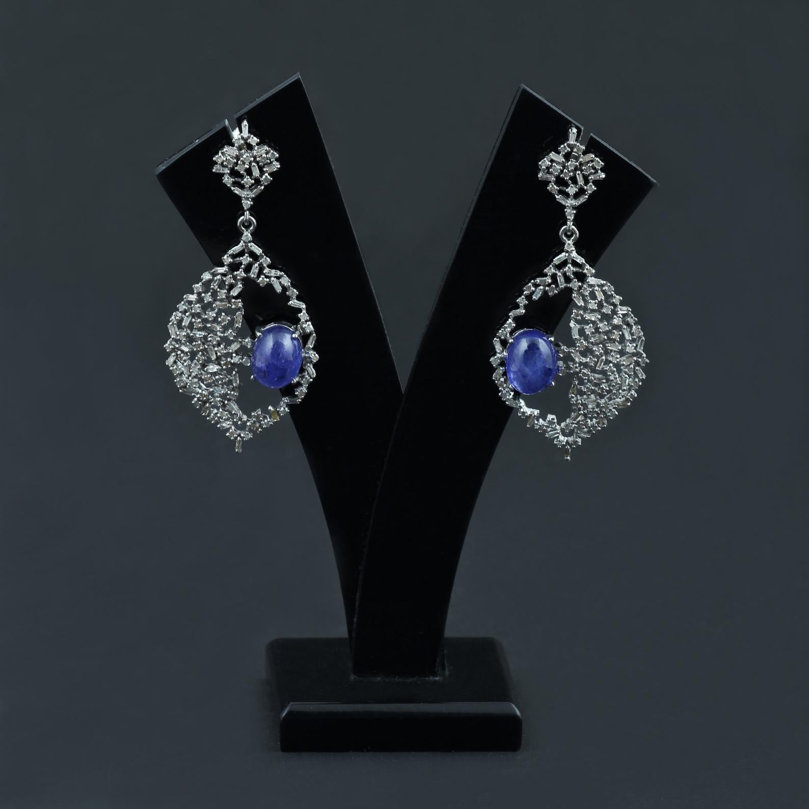 This dazzling pair of earrings are made with Large Natural Tanzanite Gemstone adorned with beautiful baguette diamonds in a modern design. These earrings reflect precise craftsmanship enough to delight any jewelry lover.