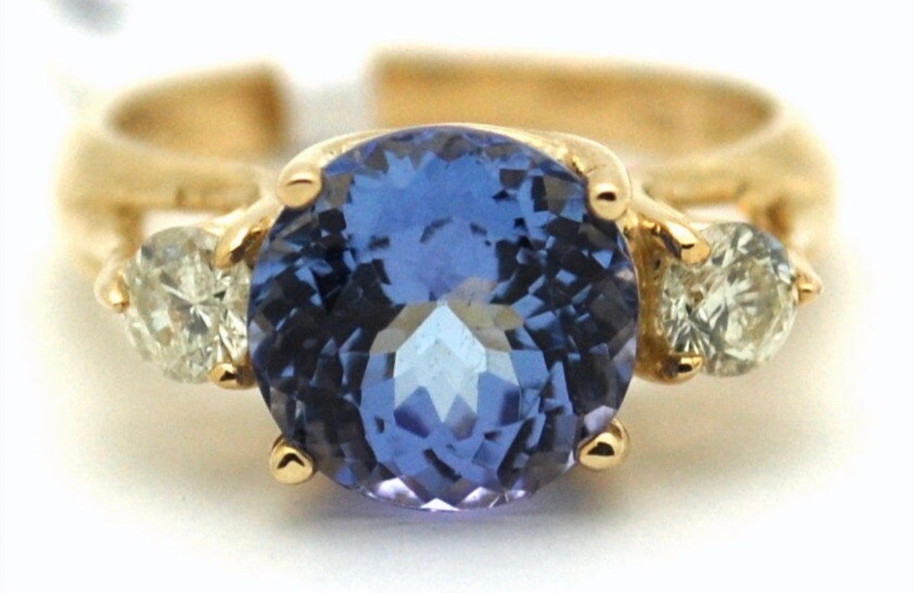 8mm roound deep violet tanzanite accompanues by natural 3mm diamonds in 18kt yellow gold, stunning three stone design ring, very sterdy and not flimsy in any way. The ring is a comfort ring style which means it feel cushion like on the finger. Its a