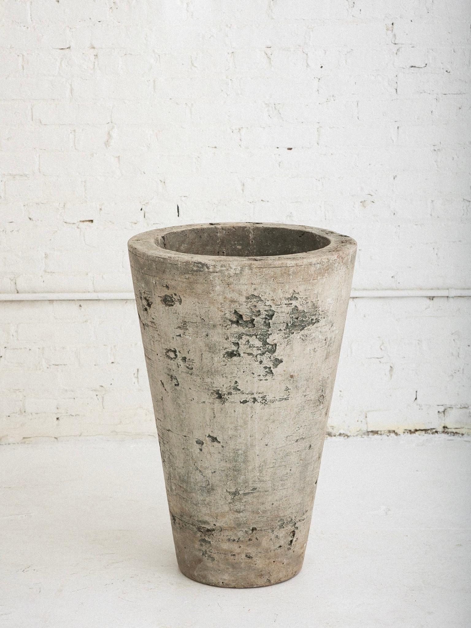A large solid concrete cast stone planter. Tapered conical Silhouette. Textured surface with a weathered patina. Drainage hole inside. Solid and heavy, circa 2005.