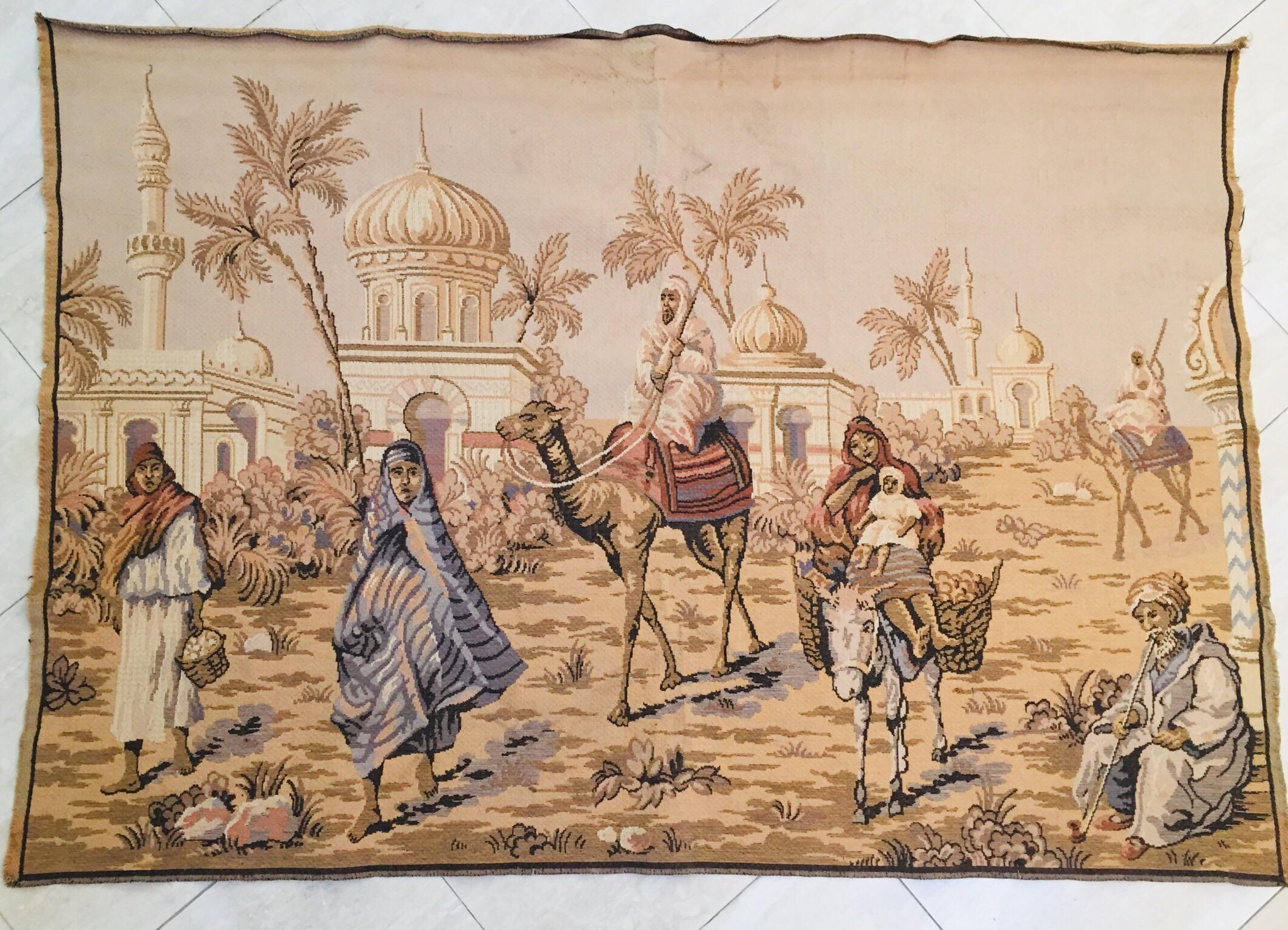 Large Aubusson style tapestry with an orientalist 19th century scene depicting Arabs figures and Middle Eastern Moorish architecture in the background.
Probably a scene in North Africa, Morocco, with a master on camel and women on a donkey and