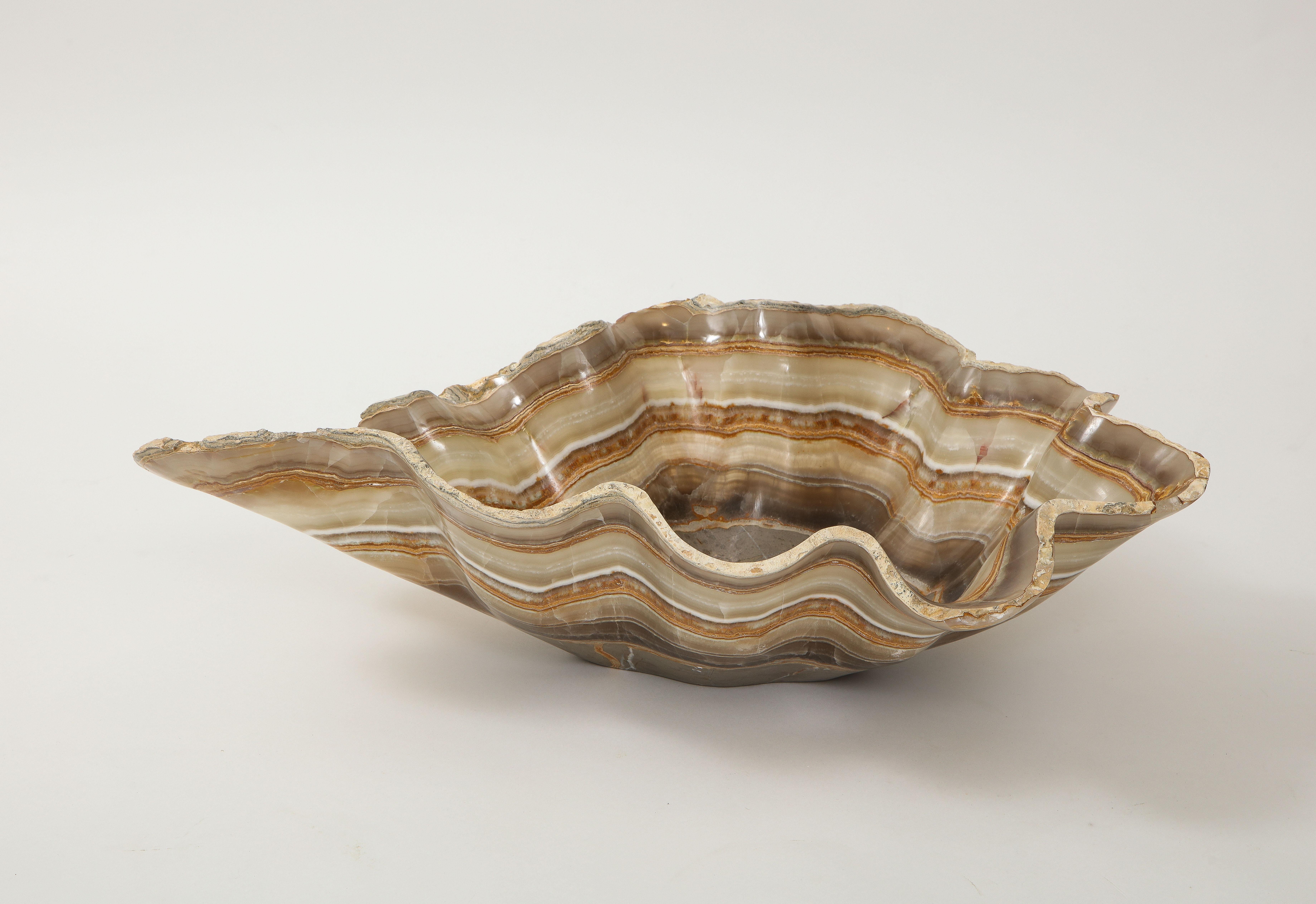 A hand carved raw edge onyx bowl or centerpiece in an impressive size with a live scalloped edge banded with rings rings of taupe, tan, griege, amber, brown and cream. Utilitarian and stunning, this centerpiece works with a variety of styles