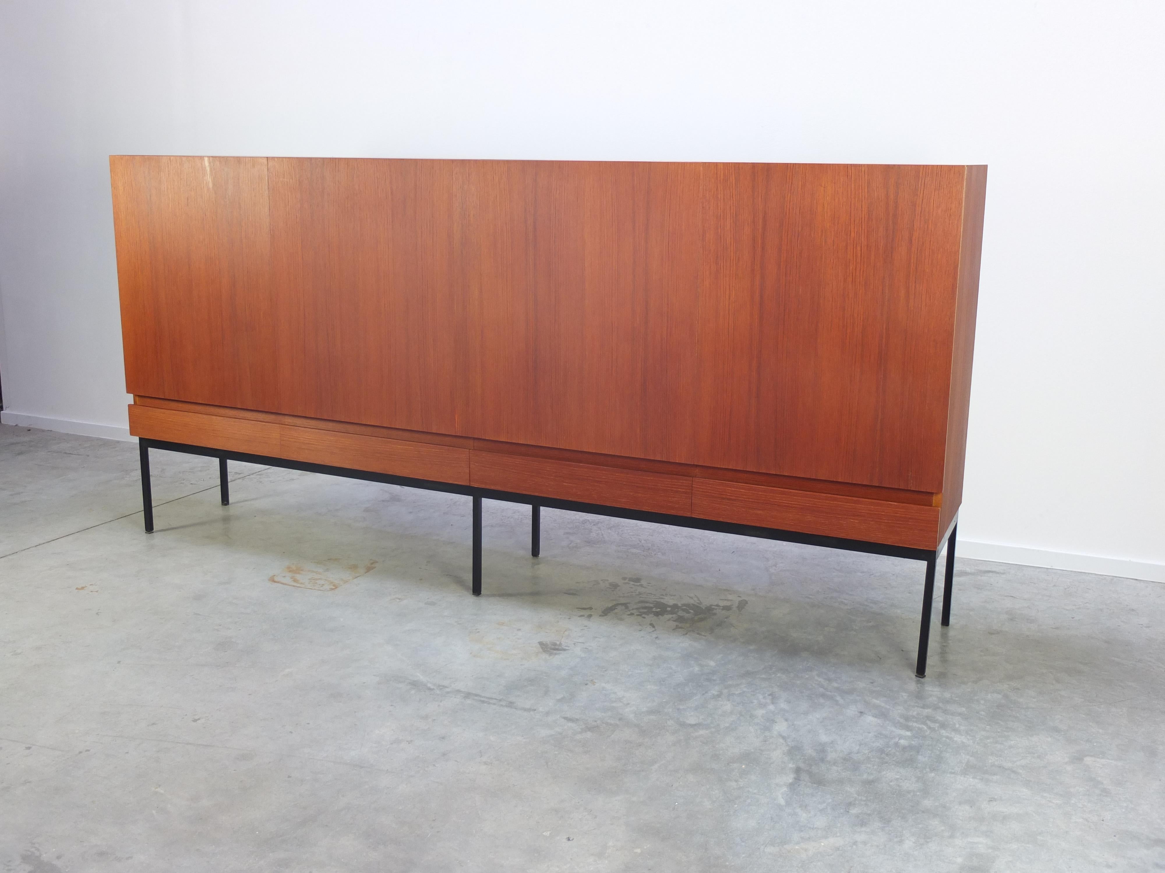 Fantastic minimalistic highboard designed by Swiss architect Dieter Waeckerlin for Behr Möbel in Germany in the 1950s. A great modernist and purist design made of teak wood on a slim black lacquered metal base. Lots of storage inside and finished