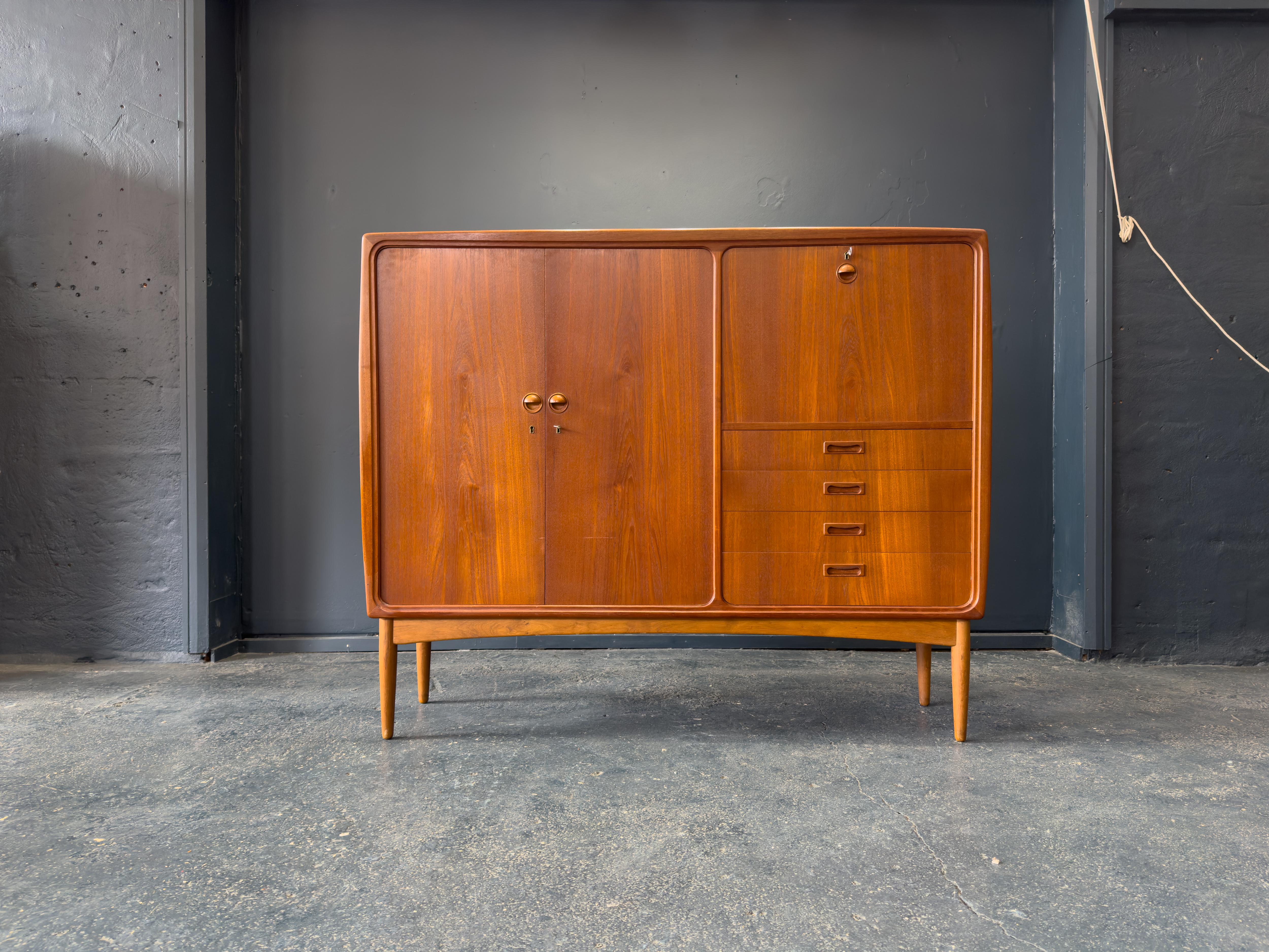 Questo mobile in teak di ottima fattura è un esempio di design danese della metà del secolo scorso, che unisce la praticità a un'eleganza senza tempo. Realizzato in teak con una ricca venatura, il mobile presenta un design senza soluzione di