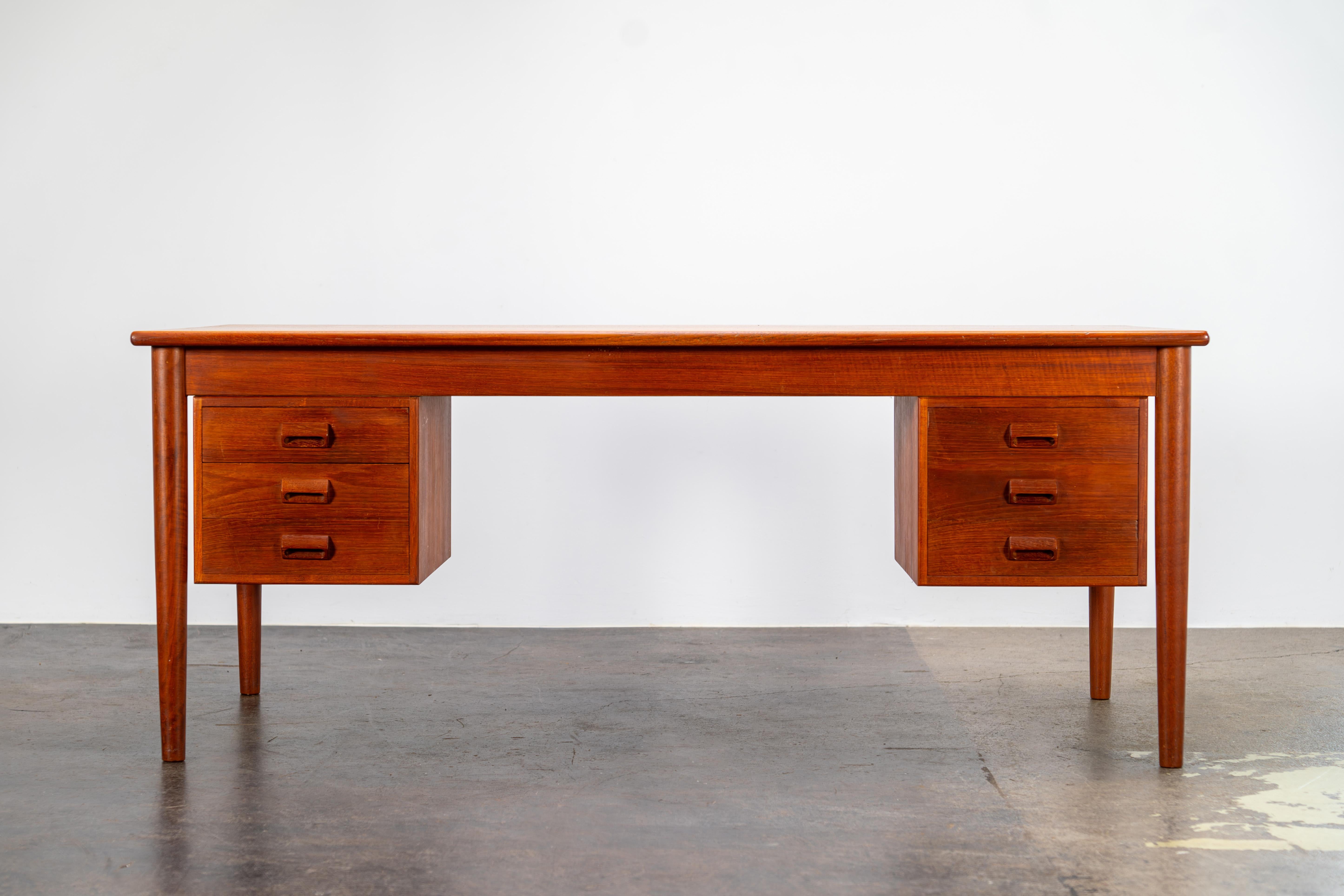 This exceptional vintage Danish desk, designed by Børge Mogensen and crafted by Søborg Møbelfabrik, embodies the timeless elegance and functionality of mid-century Scandinavian design. Made from rich teak wood, the desk features two drawer pedestals