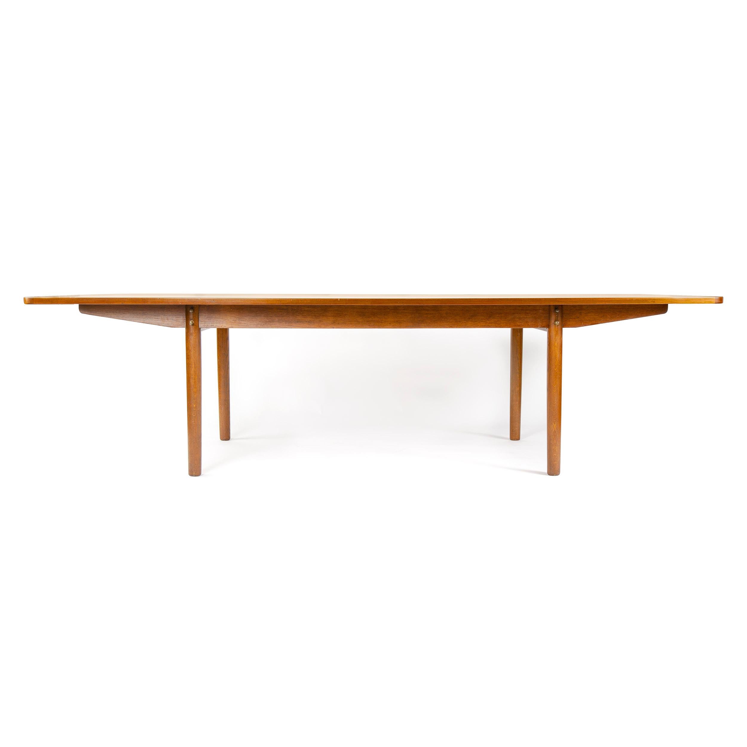 A large Scandinavian Modern dining table or conference with a bowed top crafted in solid teak wood on oak tapered dowel legs. 110.5