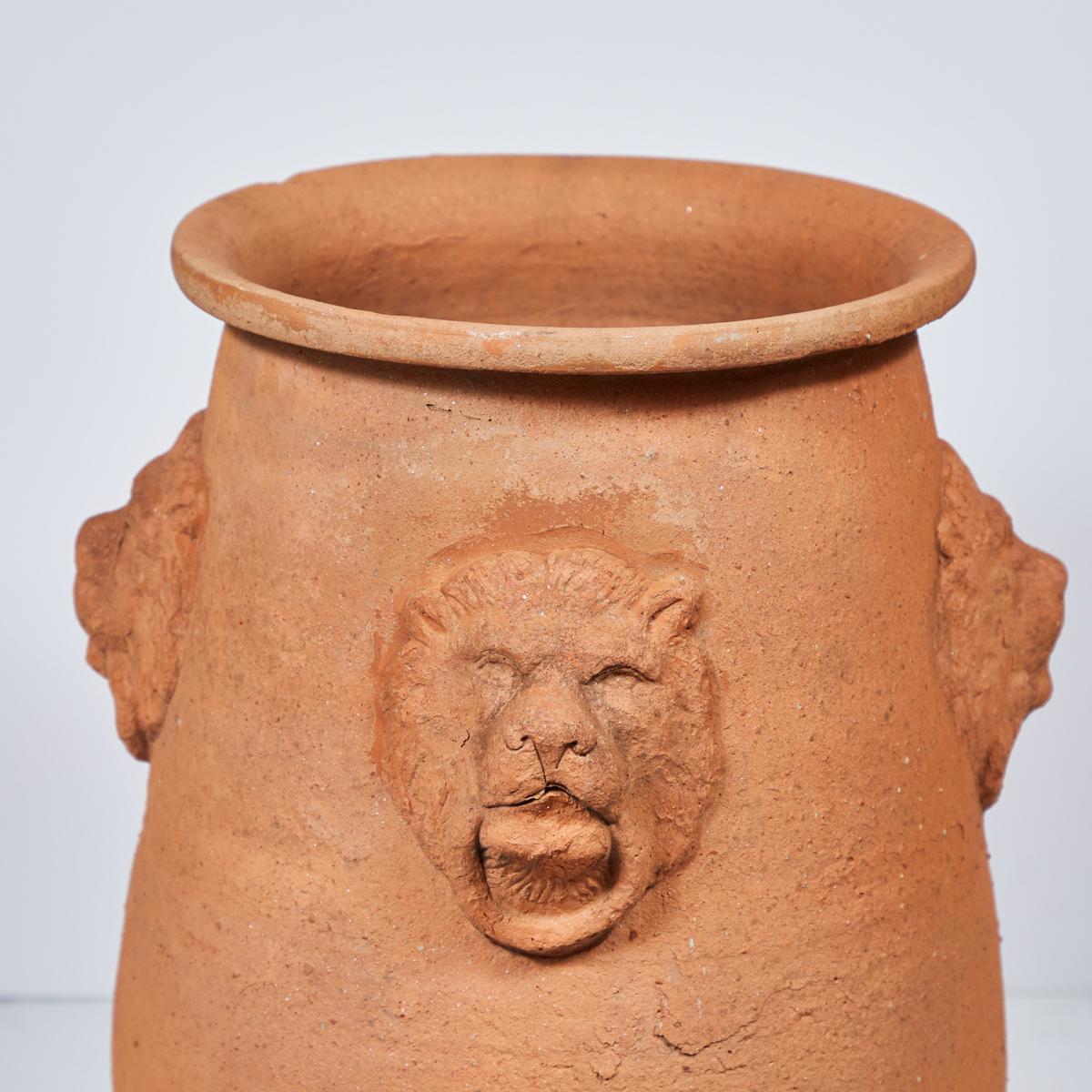 Large Italianate terra-cotta garden pot from early 20th-century England. With a slightly tapered oblong shape, rounded circular lip and four lion's head ring-pull carvings, the vessel has a rustic and classical feel.

England, circa