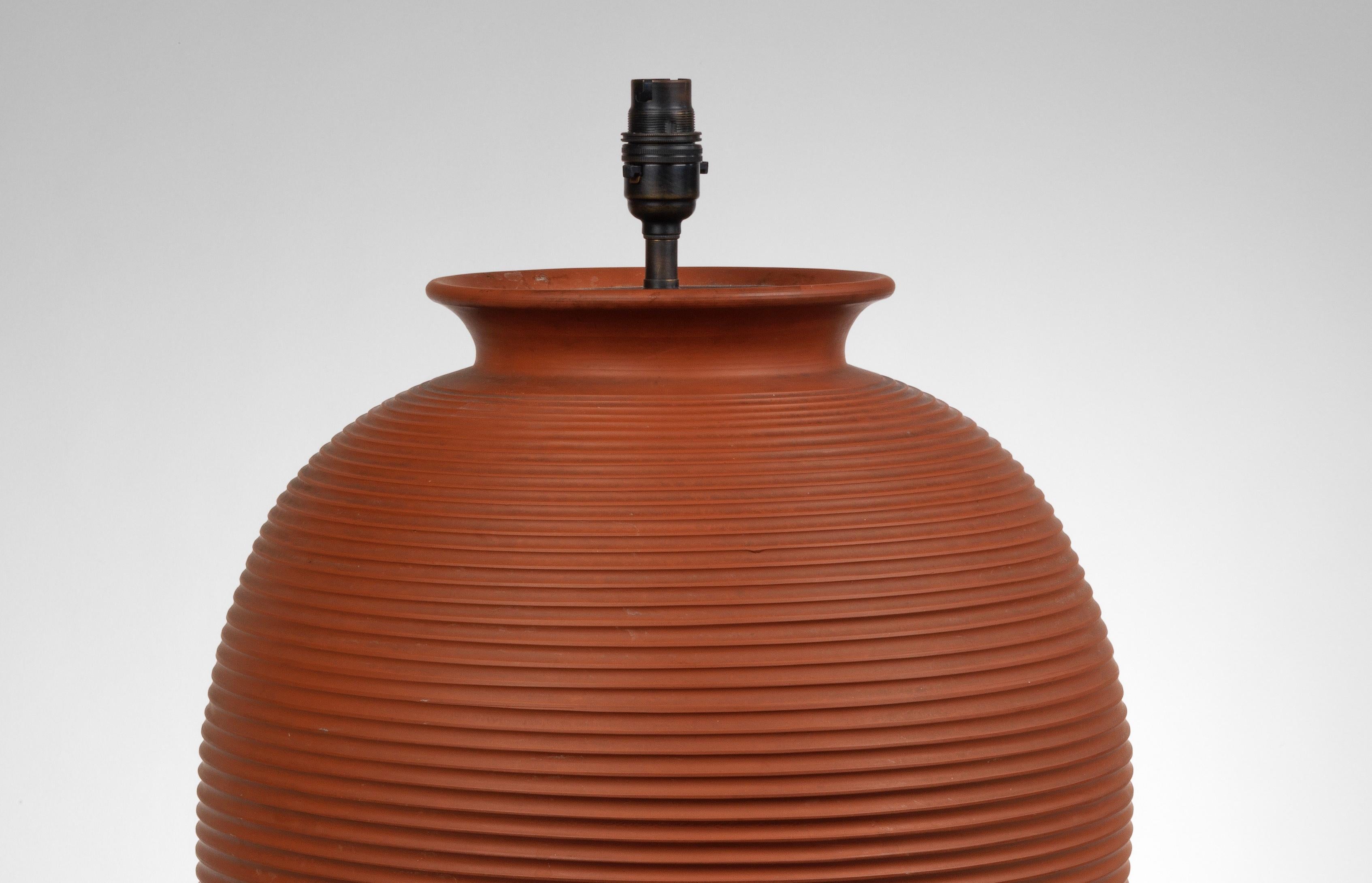 An attractive large scale French terracotta vase with ribbed decoration.

Now mounted as a lamp.

Height of vase: 21 in (53 cm) including base, excluding electrical fitments and lampshades.

All of our lamps can be wired for use worldwide. A variety