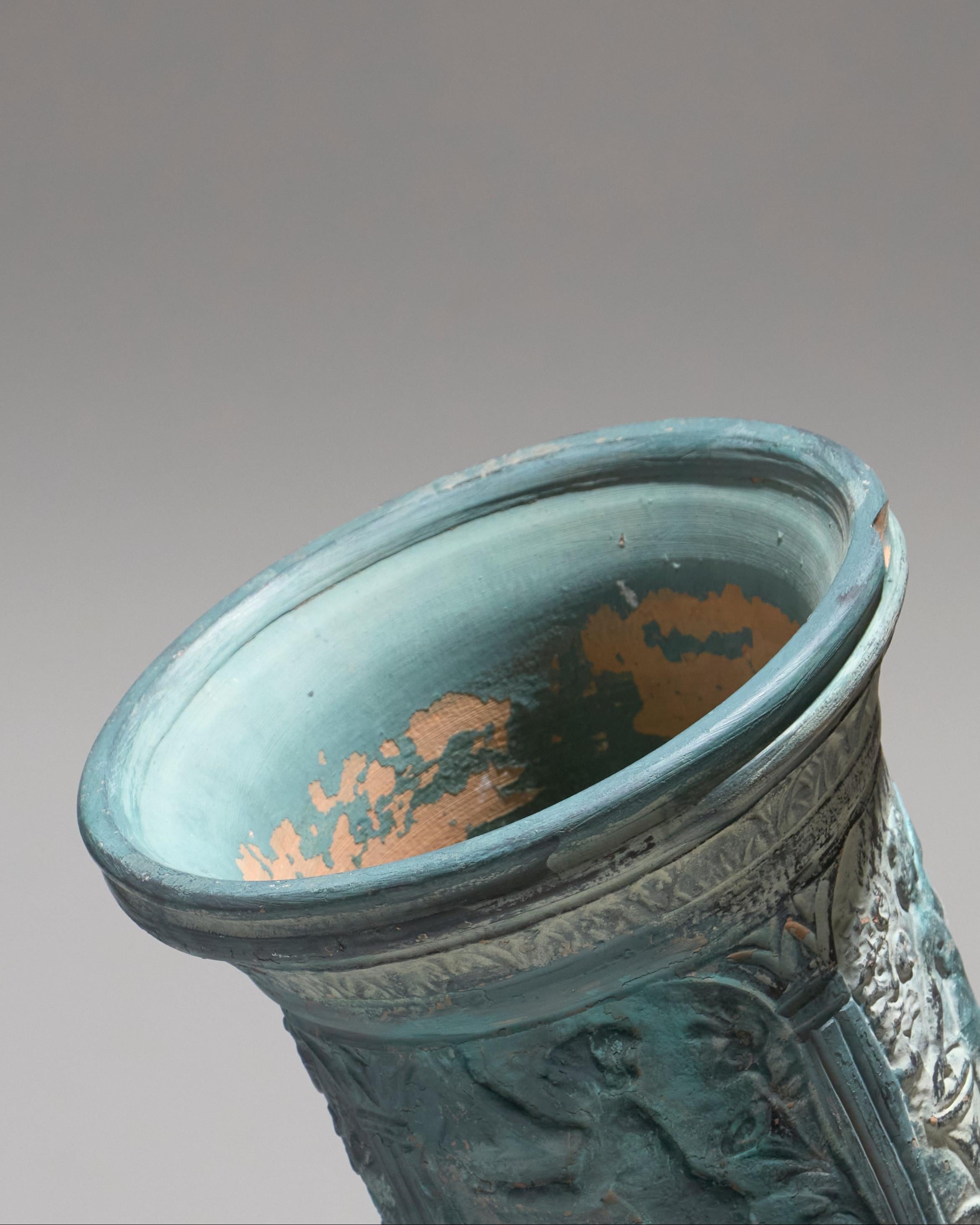 Vase de belle dimension en terre cuite couvert vert turquoise, orné d’un décor inspiré de la mythologie. Bon état général, avec quelques manques de peinture visibles sur la surface.