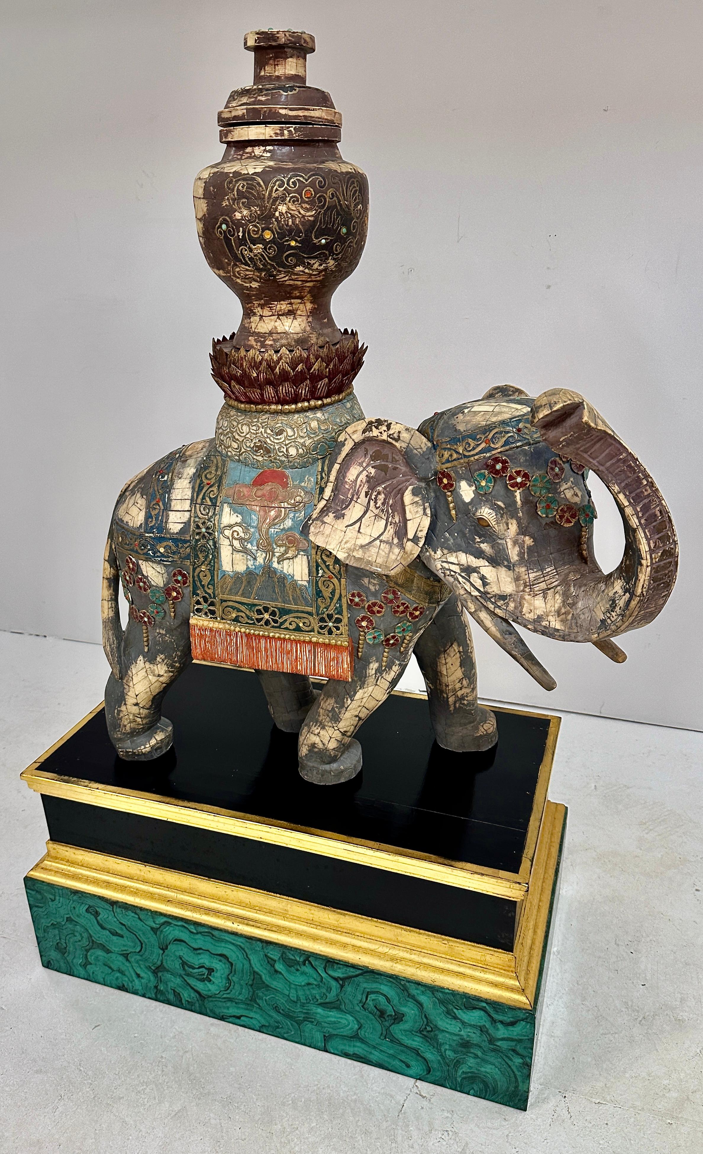 A very impressive sculpture of an Asian elephant formed from bone tiles decorated with hand painting and applied elements forming a traditional howdah. The former owners commissioned an elegant custom stand featuring a hand painted faux malachite