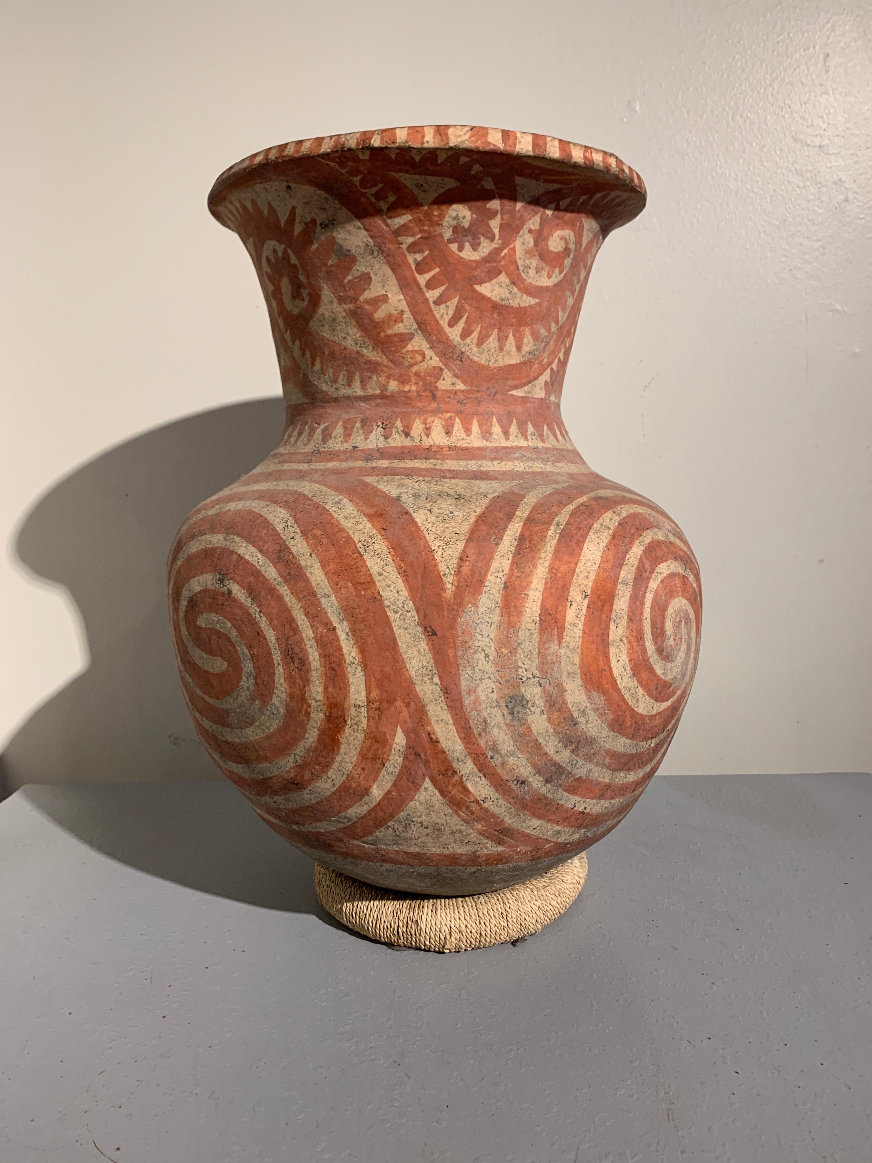 A massive Ban Chiang culture painted pottery vessel, circa 300 BC, Thailand.

The large storage jar painted with a bold spiral pattern in red ochre on a buff ground. The spiraling patterns taking up most of the body of the vessel are reminiscent