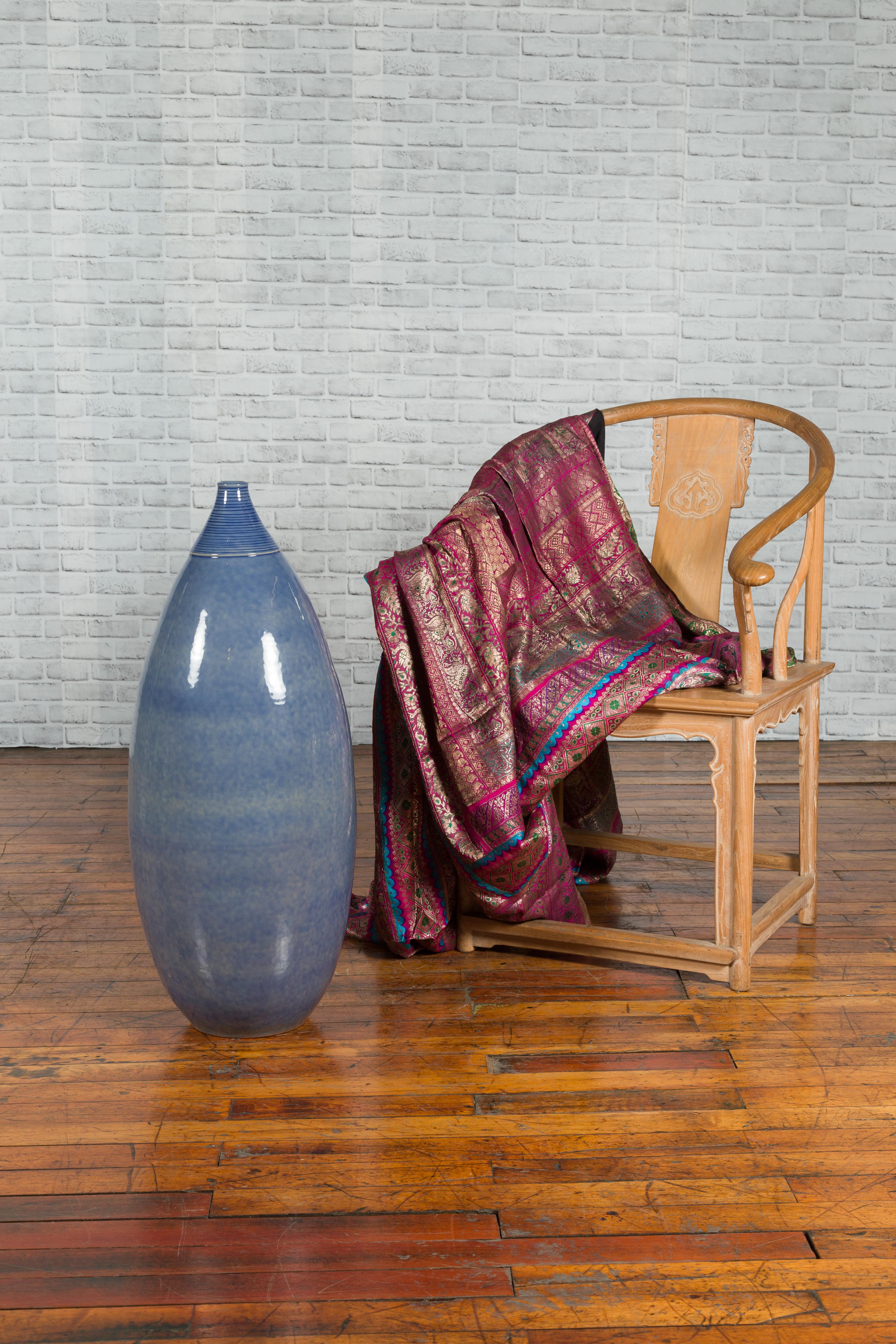 Un grand vase en céramique artisanale avec une glaçure bleue douce et un col nervuré. Elegant et discret, ce grand vase en céramique capte le regard par sa silhouette harmonieuse et sa glaçure bleue subtilement variée. Son ouverture étroite de 2