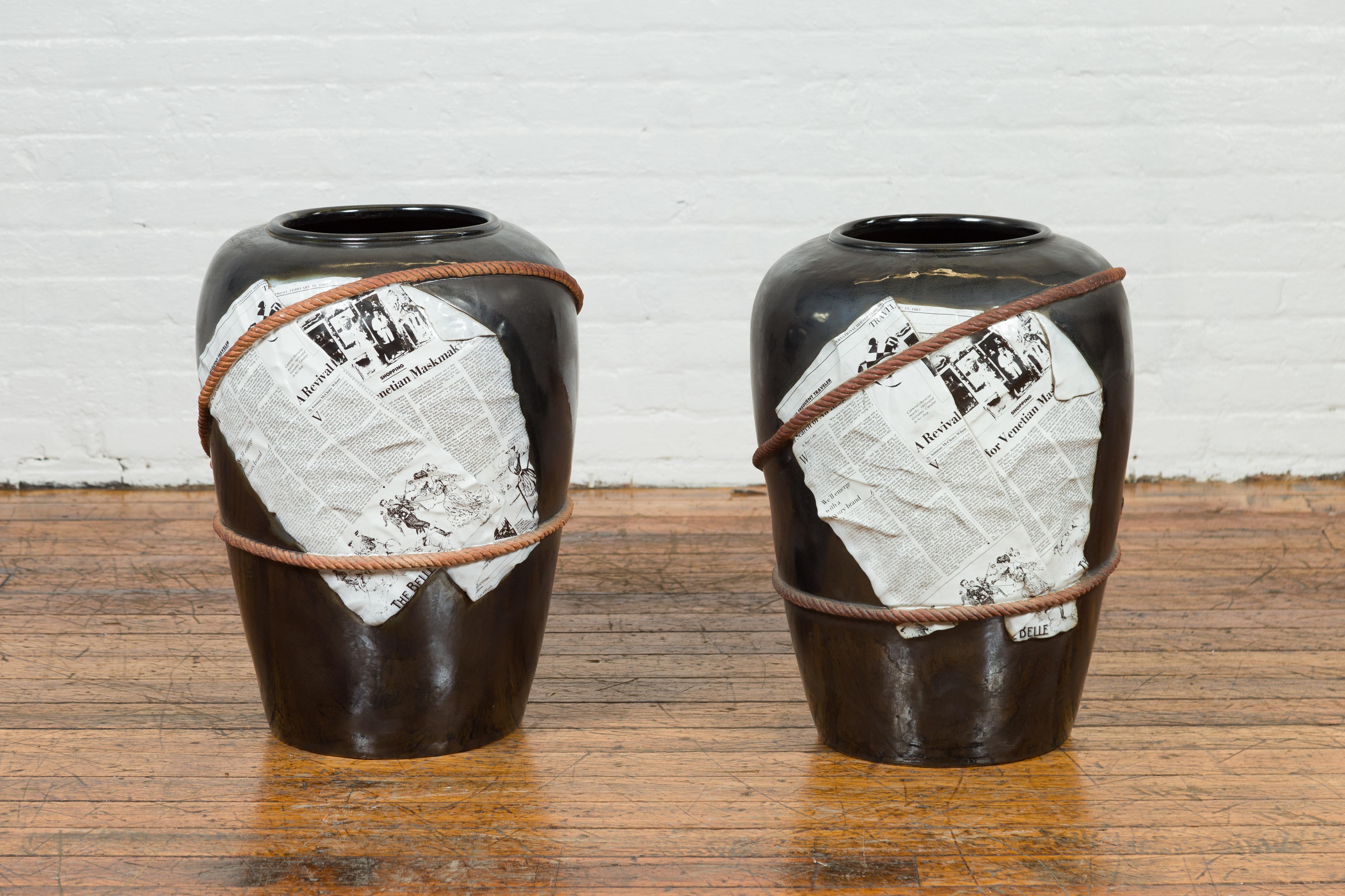 A large contemporary Thai exterior flower vase with black patina, rope and newspaper motifs. We have two available, priced and sold $1,100 each. Created in Thailand, each of these large exterior flower vases attracts our attention with its clean