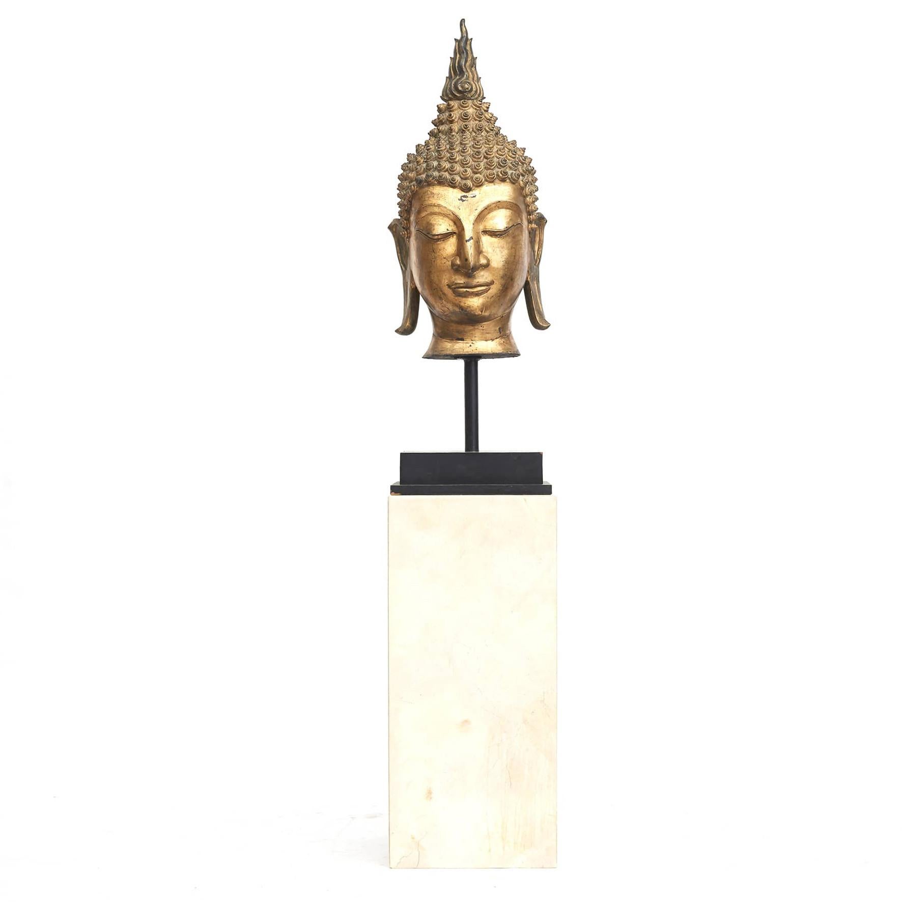 A large gilt bronze head of Buddha on black square base. Thailand c. 1900.
Decorative with good patina.

Measures: Height head: 96 cm.
Height incl. base: 135 cm.
Total height incl. plinth: 235 cm.