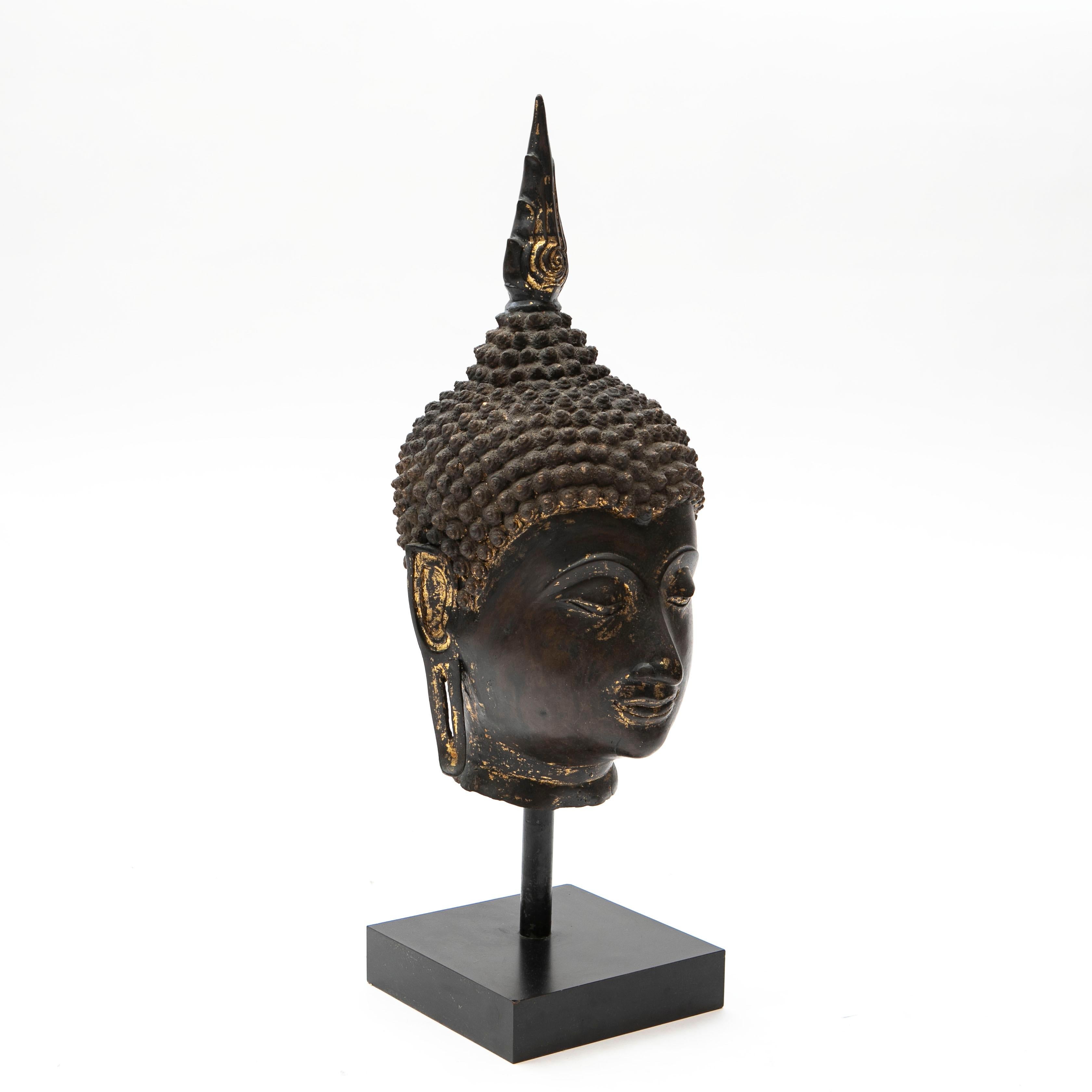 Thai bronze head of a Buddha with some of the original gilding still remaining.
Mounted on a black painted metal stand.

Height incl. stand: 78 cm / 30.7 inch.  Height excl. stand: 60 cm / 23.6 inch.

Thailand (Siam), approx. 1900.