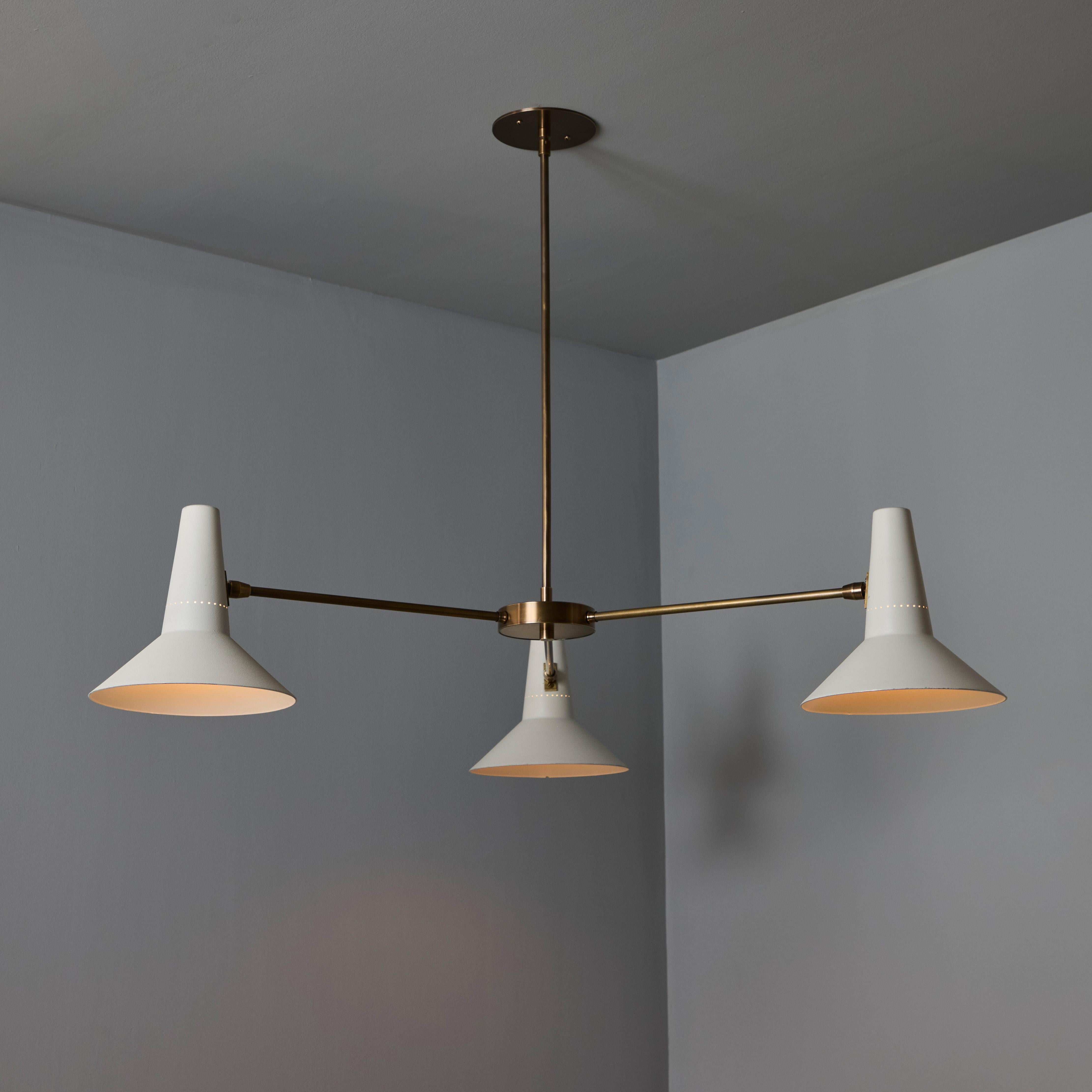 Grand lustre à trois cônes en blanc et laiton dans le style de Giuseppe Ostuni.

Exécuté avec des abat-jours perforés peints en blanc des années 1950 provenant d'Italie et un cadre en laiton patiné fabriqué sur mesure. Un lustre raffiné d'une taille