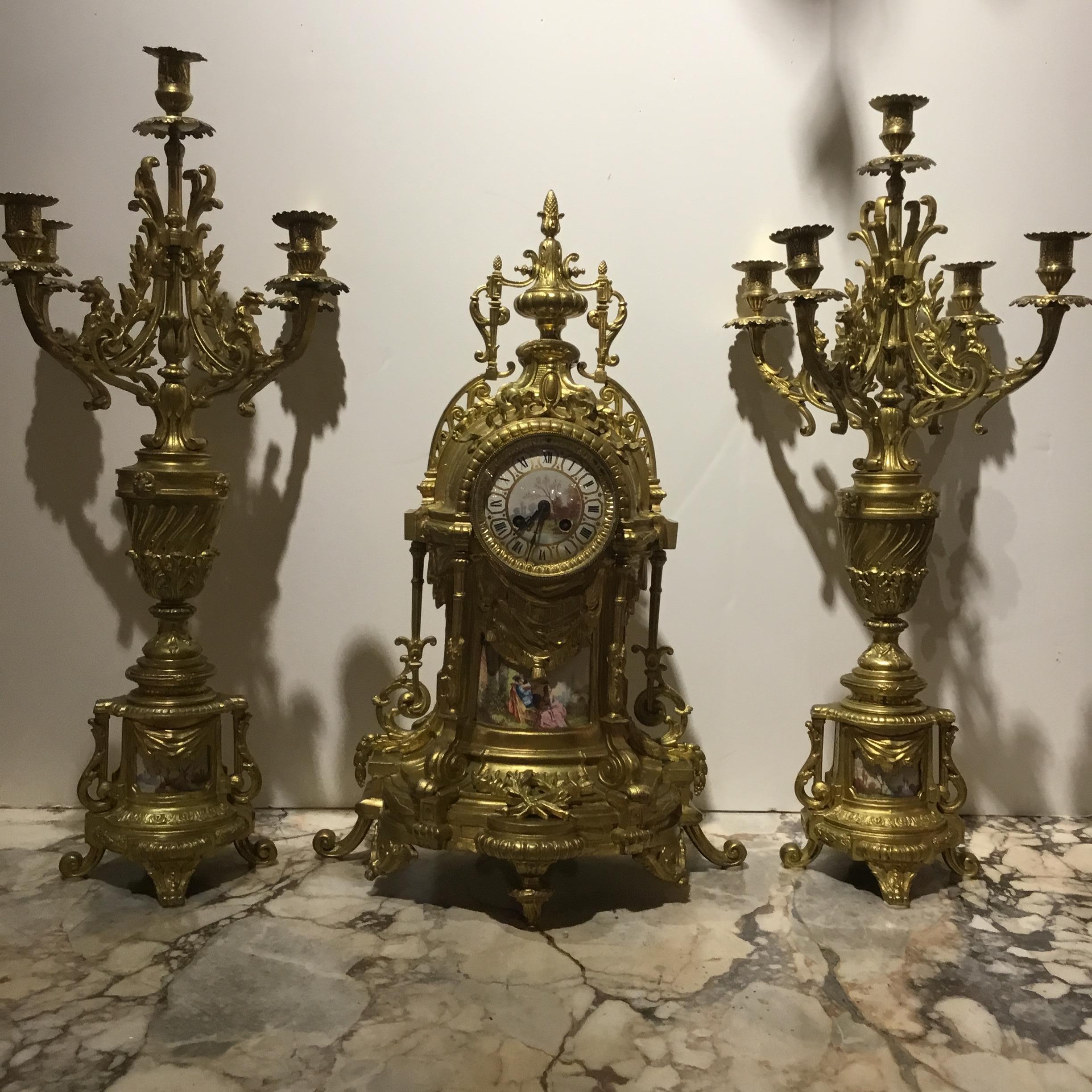 Louis XVI style garniture set. Torch and quiver design is  centered at 
Bottom of the clock. A hand painted garden scene is presented at the
Lower portion of the clock and a beautiful hand painted face depicts
The French landscape. An urn is