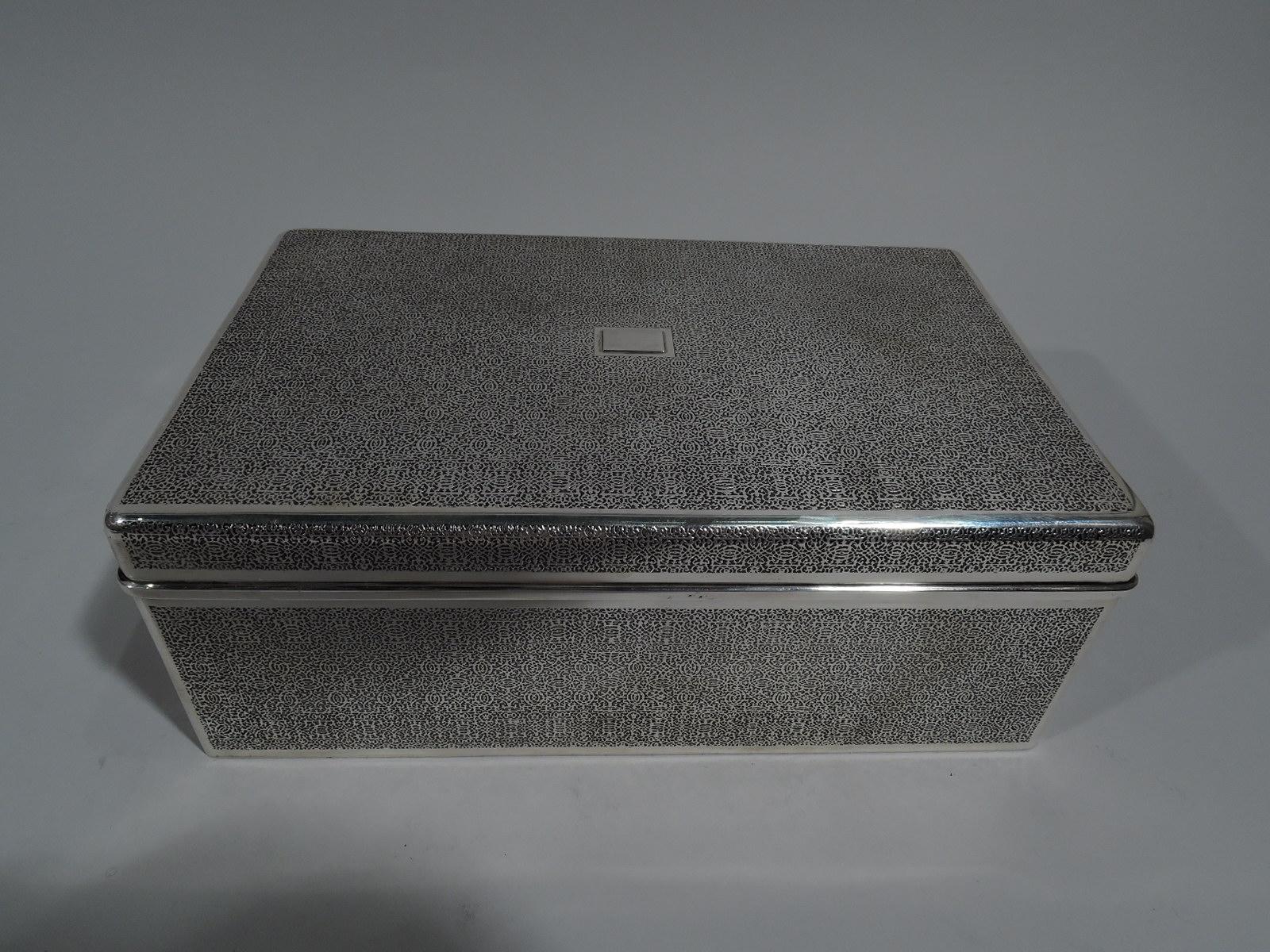 Large sterling silver box. Made by Tiffany & Co. in New York, circa 1927. Rectangular with straight sides and curved corners. Cover flat and hinged with molded rim. Fine and dense acid-etched all-over scrollwork mesh, a wonderful lacy pattern. Box