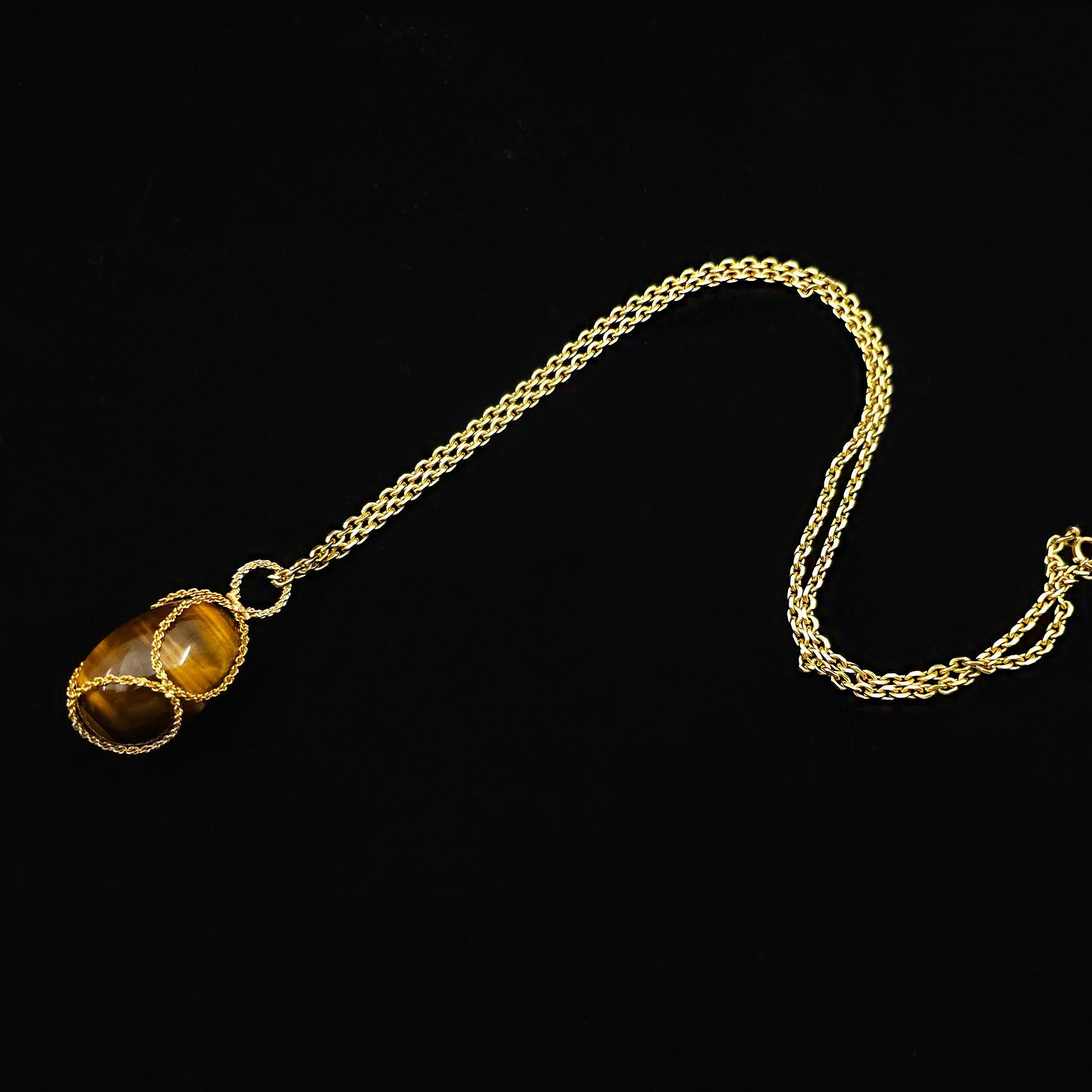 A Tiger’s eye and 18 karat gold egg pendant. (Chain not included)

This bold and captivating pendant features a large polished tiger’s eye egg suspended within a basket of rope textured 18 karat gold. The egg fits securely in the basket but also