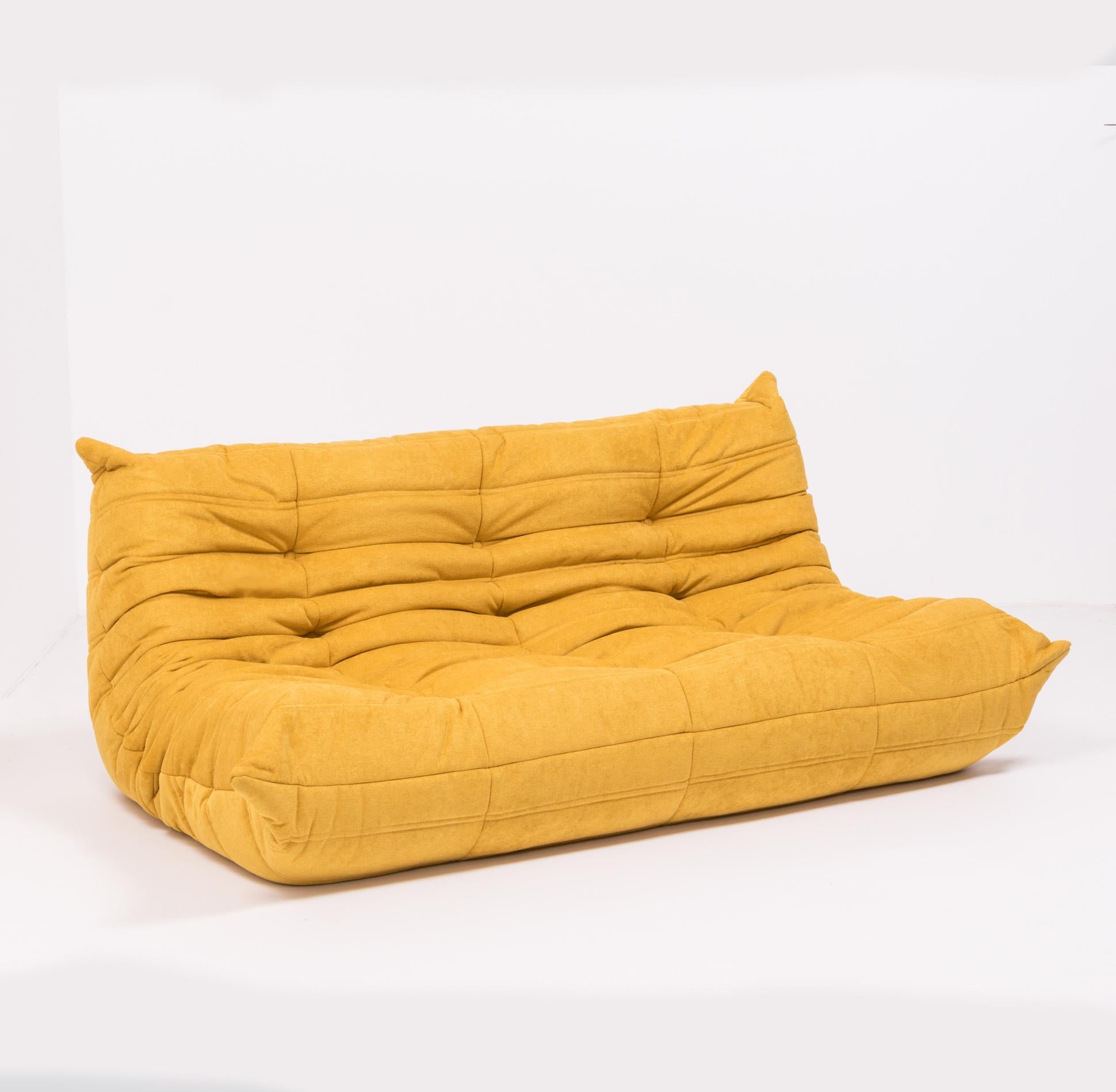 The iconic Togo sofa, originally designed by Michael Ducaroy for Ligne Roset in 1973, has become a design classic.
 
This large 3-seat model has been newly and completely reupholstered in marigold yellow Liberto fabric which can be spot cleaned