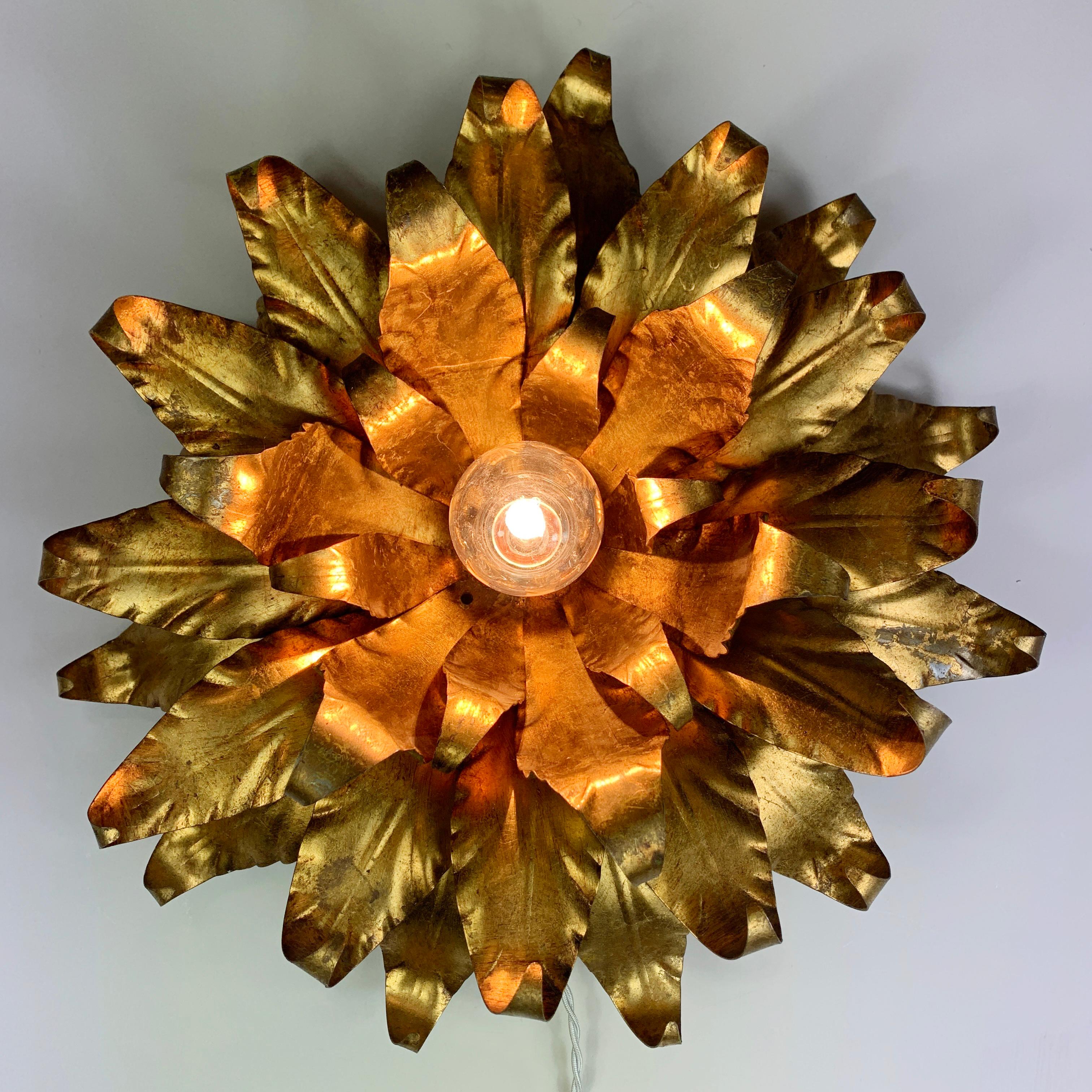 Applique / plafonnier italien à fleurs dorées des années 1960.

Fabuleux luminaire en faïence dorée en forme d'efflorescence de feuilles ou de fleurs, il est muni d'une douille pour ampoule E27 en son centre. 

Mesures : 47cm de largeur, 17cm de