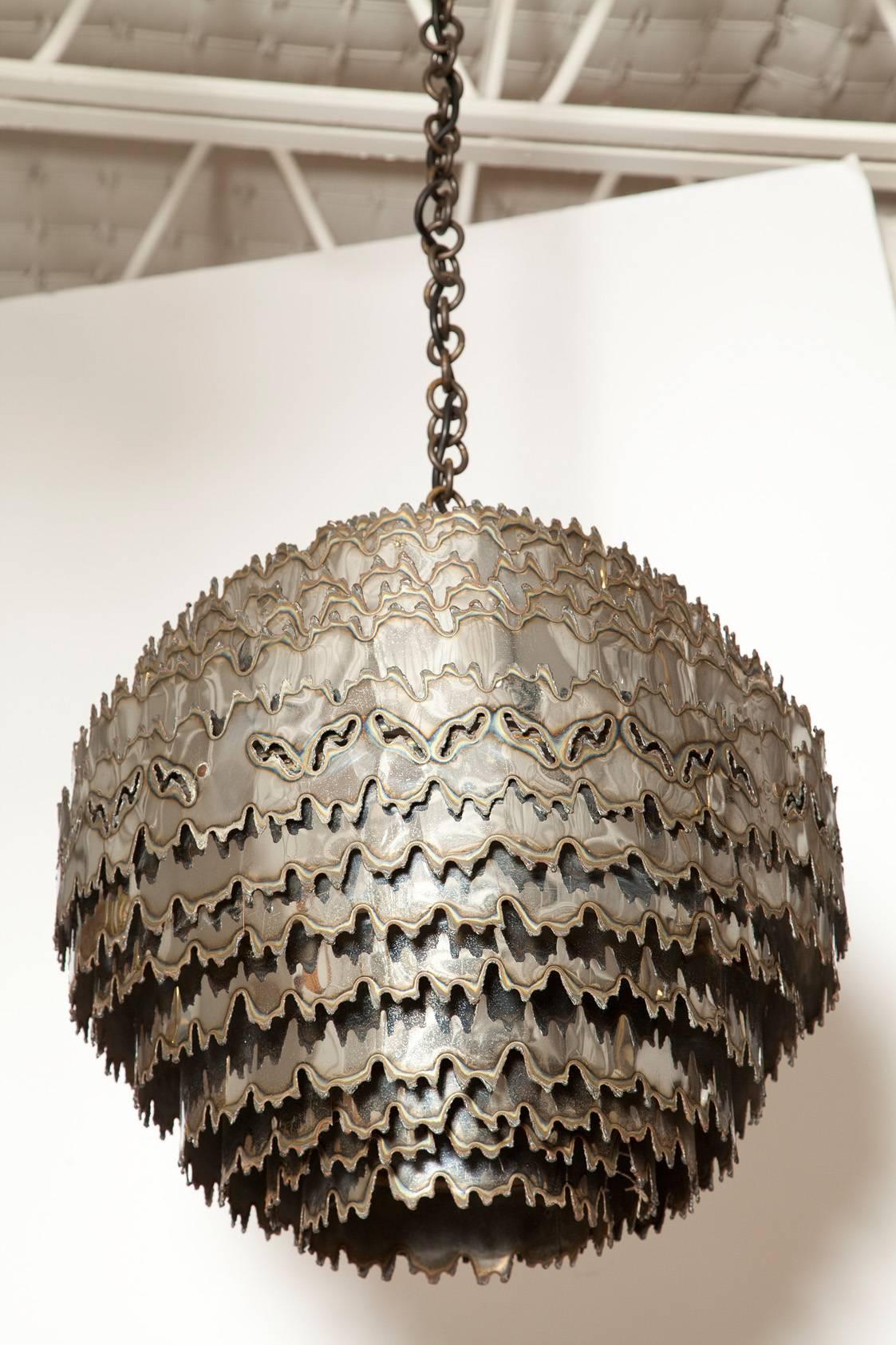 This large 1970s chrome finished, torch cut orb chandelier is one of the finest examples of Tom Greene's work for Feldman Lighting. Re-wired and-polished, with approximately 34 inches of original chain and canopy.