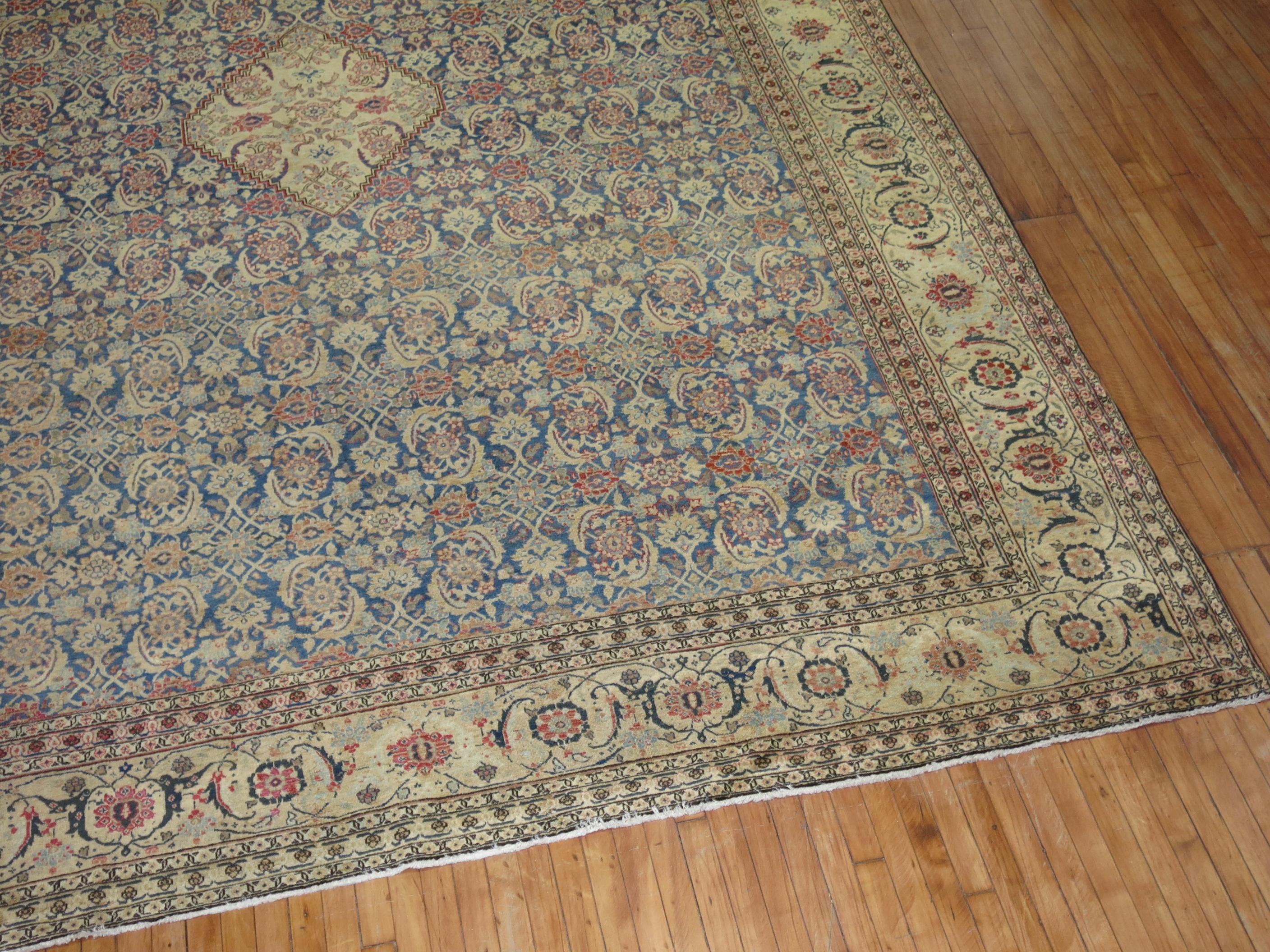 A large oom size antique Persian Tabriz Oriental rug woven early 20th century. Classic, Elegant, and the quality is there. the field is blue, a small beige medallion in the center of the field, accents in red, and pink A rug for the