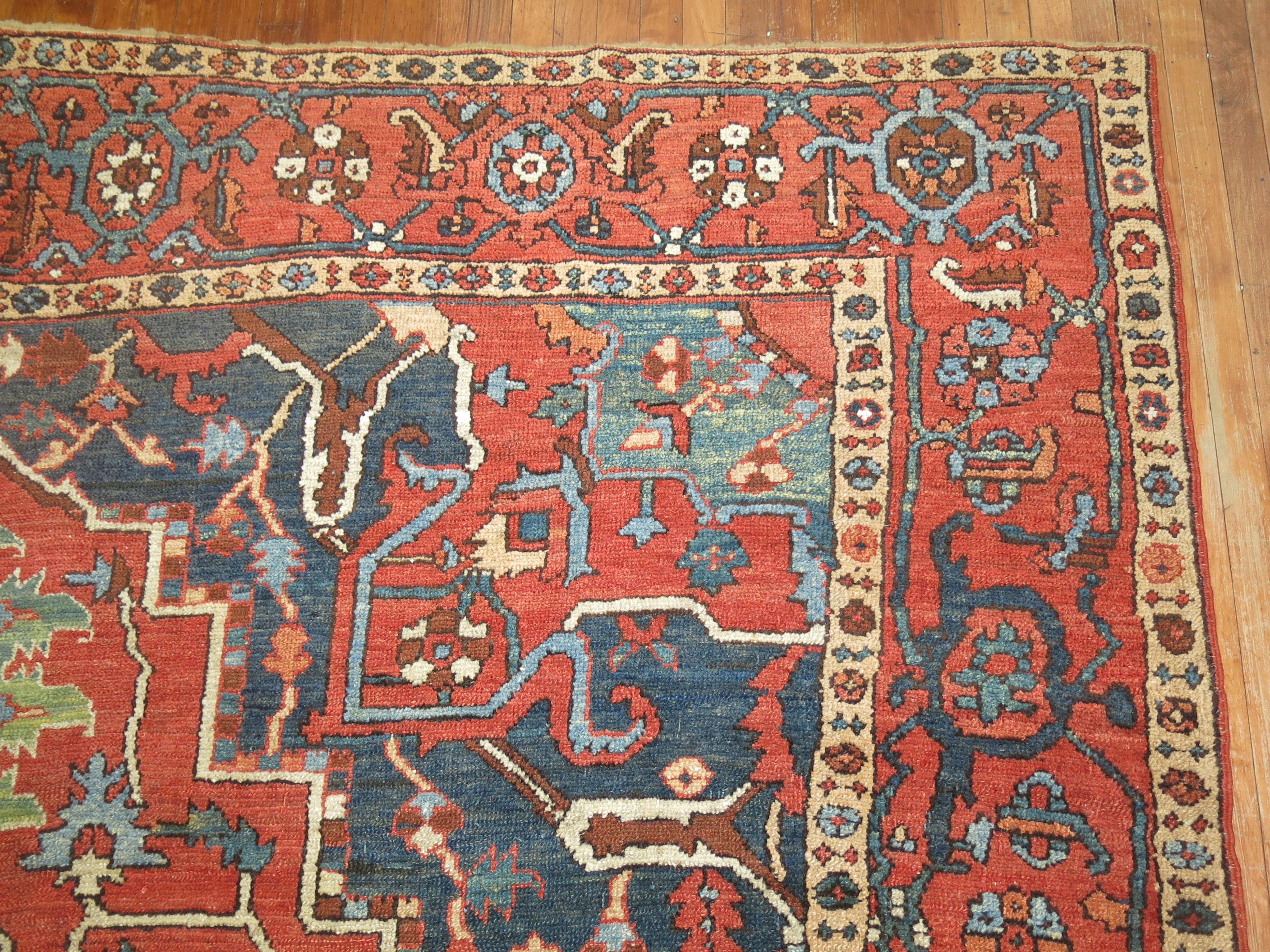 Rare tapis persan Heriz traditionnel ancien de 10 x 14. Champ et bordure orange, médaillon anthracite, accents en kaki, bleu et vert 

circa 1920, mesures : 9'11