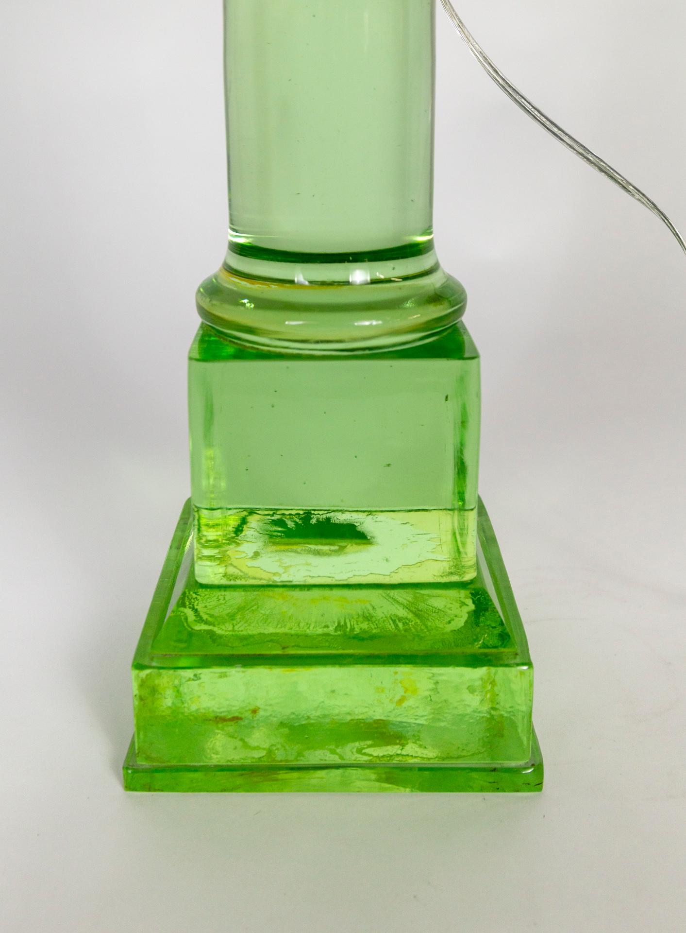 A striking column in translucent, green glass that is French wired as a lamp. It takes on different looks depending on what is behind it and on what ground it sits; shifting color and value. It's comprised of stacked, molded pieces. New brass
