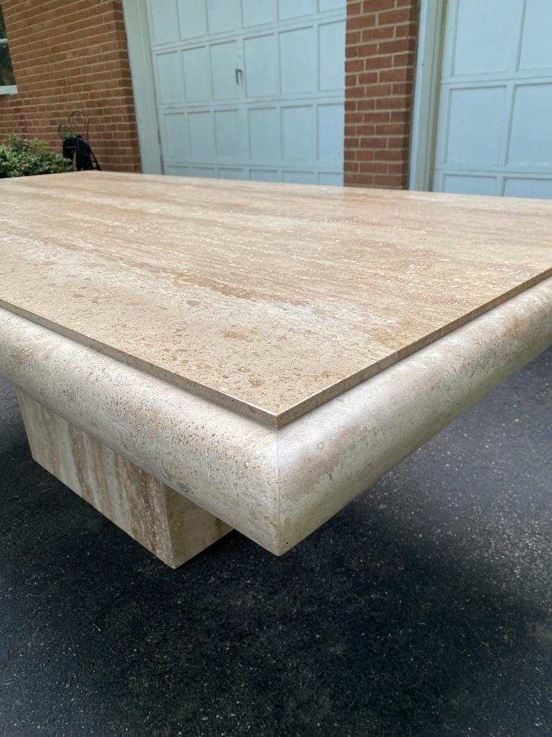 This Large Travertine Beveled Edge Single Pedestal Rectangle Dining Conference Table is a statement of timeless elegance. Crafted with meticulous attention to detail, the table boasts a stunning travertine stone top with finely beveled edges. The