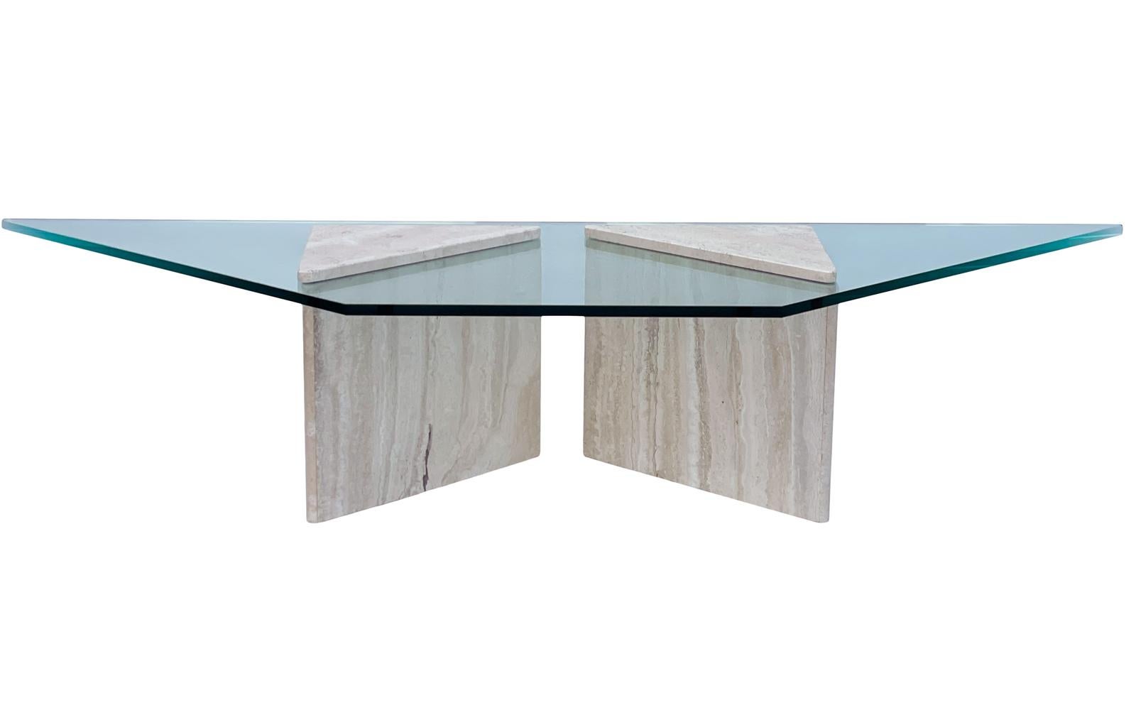 An extra long coffee table from Italy circa 1970's. It features 2 triangular travertine pedestals supporting a thick clear glass top.