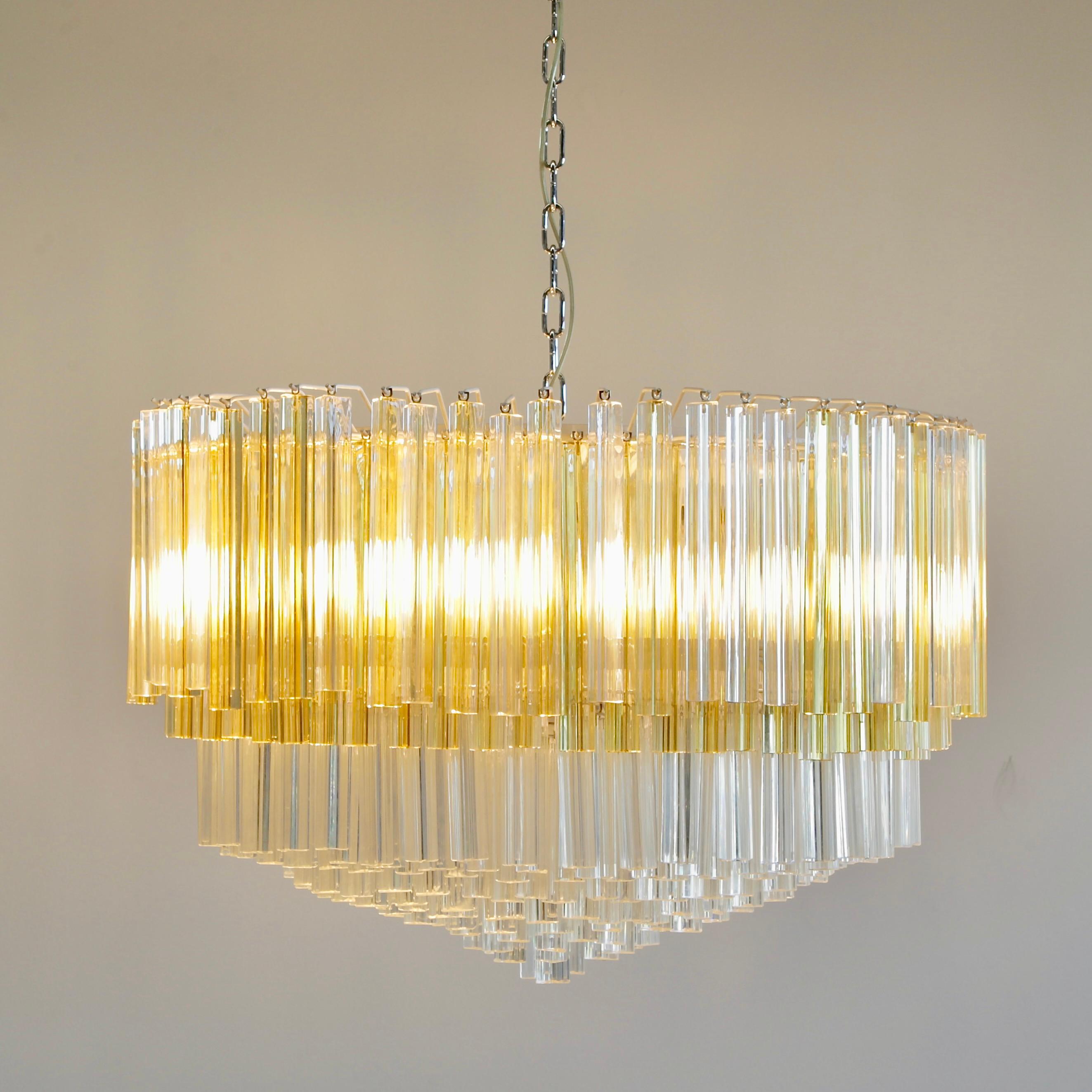'TRILOBI' glass chandelier. Italy, Murano.

Large glass chandelier with clear and amber coloured 'Trilobi' glass made in Murano, c. 1980. Multi-tier glass chandelier with white metal frame, twelve E27 light fittings and some 300 Trilobi glass