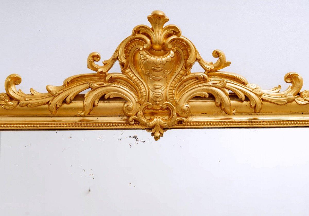 Ein sehr eleganter, großer Spiegel aus Holz, vergoldet mit 24 Karat Blattgold.
Der Giebel zeigt eine Muschel, die mit Schriftrollen und Blumenmotiven verziert ist.
Der originale Quecksilberspiegel wird durch einen schönen Fries aus vergoldeten