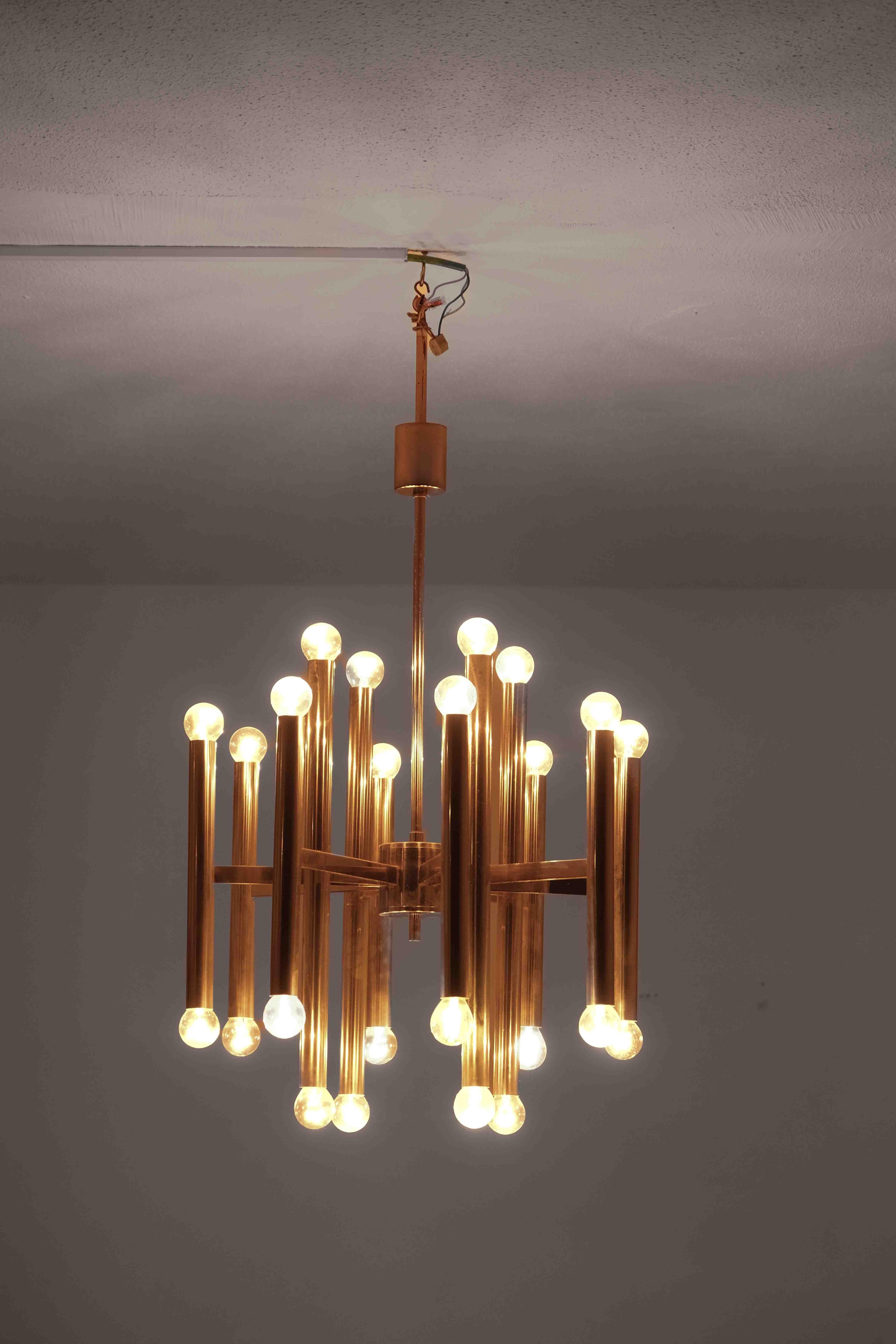 This striking chandelier, crafted in the 1960s, is a quintessential example of Gaetano Sciolari’s innovative design approach. The structure features a symmetrical assembly of 12 slender brass rods, each tipped with 2 glowing bulb, creating a radiant