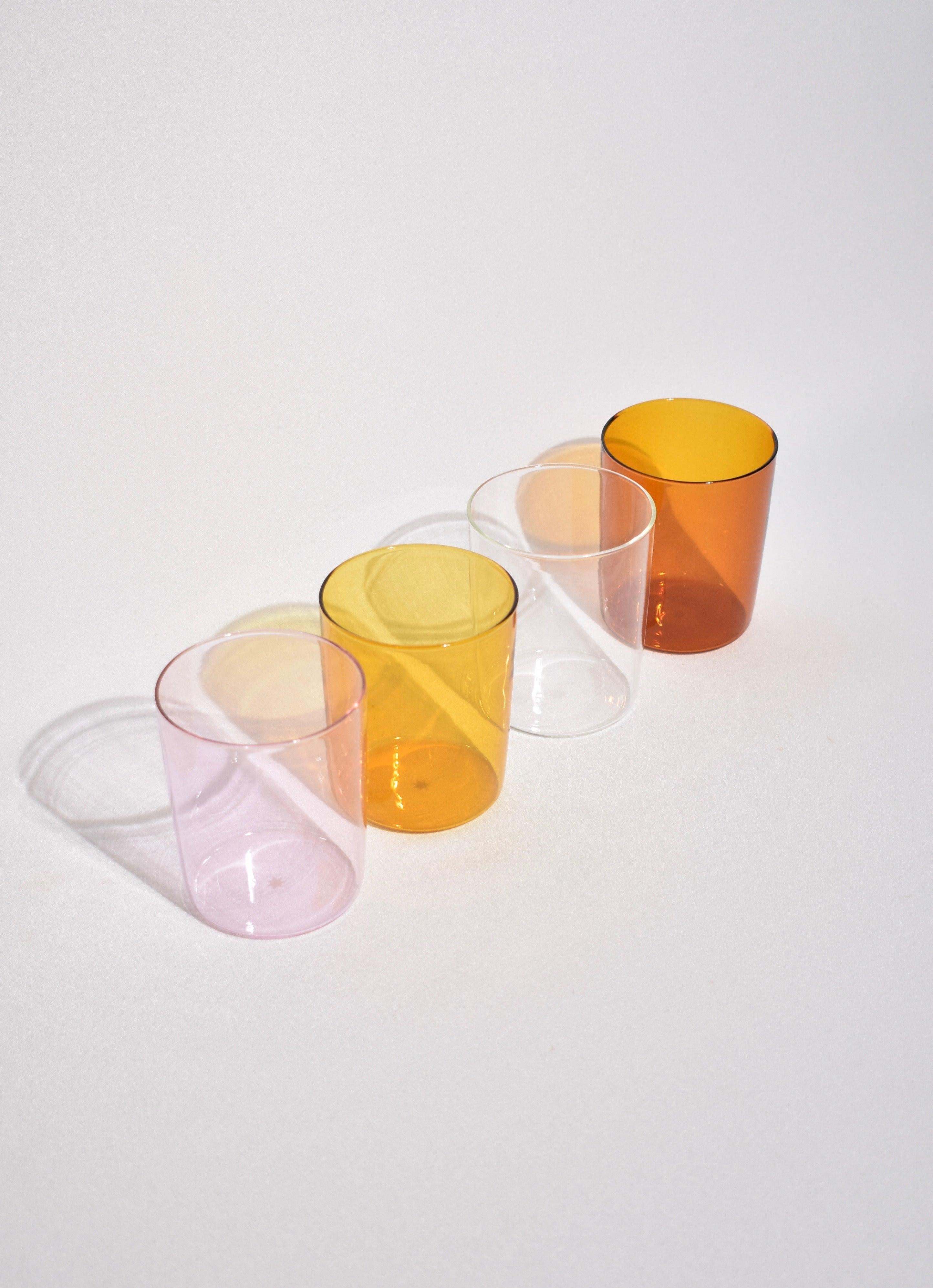 Glass tumbler set in pink, miel, clear, and amber by Maison Balzac. 

Food grade colored glass, individually mouth blown. 
Heat and cold resistant.
Hand wash recommended.
450ml capacity
Dimensions
Height: approximately 4 in (10.16 cm).