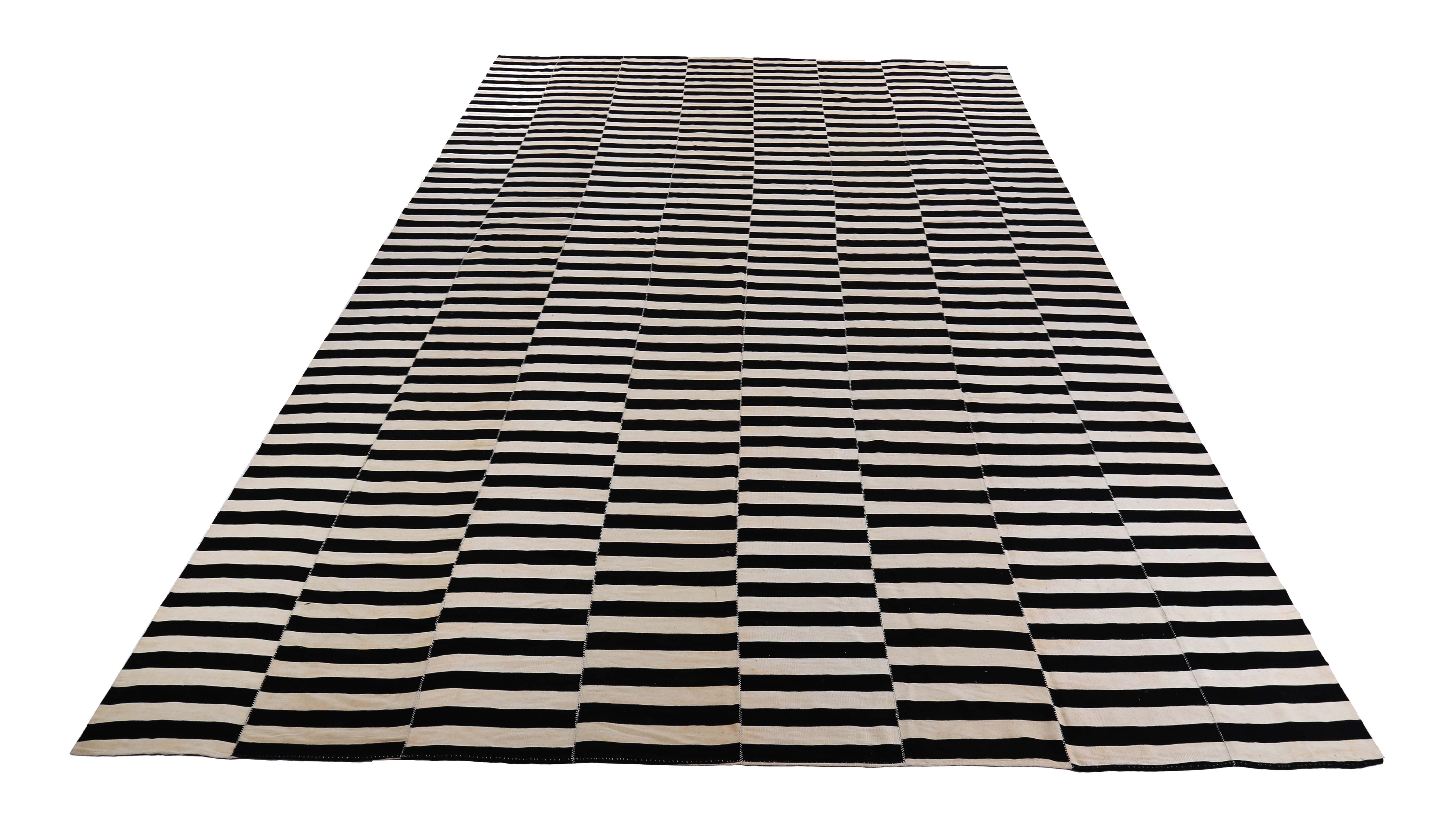 This exquisite Turkish rug is handwoven with the finest sheep’s wool, making it an ideal addition to any modern, contemporary, or rustic space. The Kilim flat-weave design showcases black stripes over an ivory field, which adds elegance to any room.