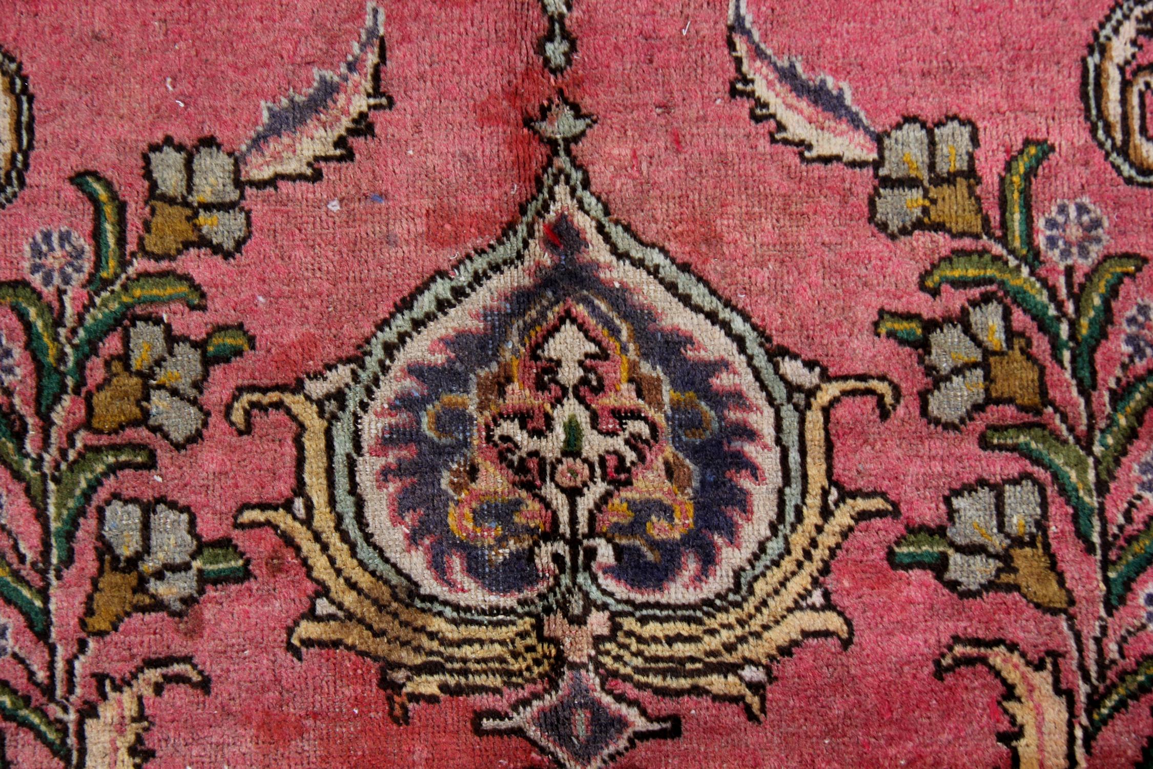This luxurious carpet has been woven with a rich wine-red background with cream, blue, green and pink accents that make up the intricate, highly-decorative medallion and surrounding design. The floating medallion and complex surrounding patterns