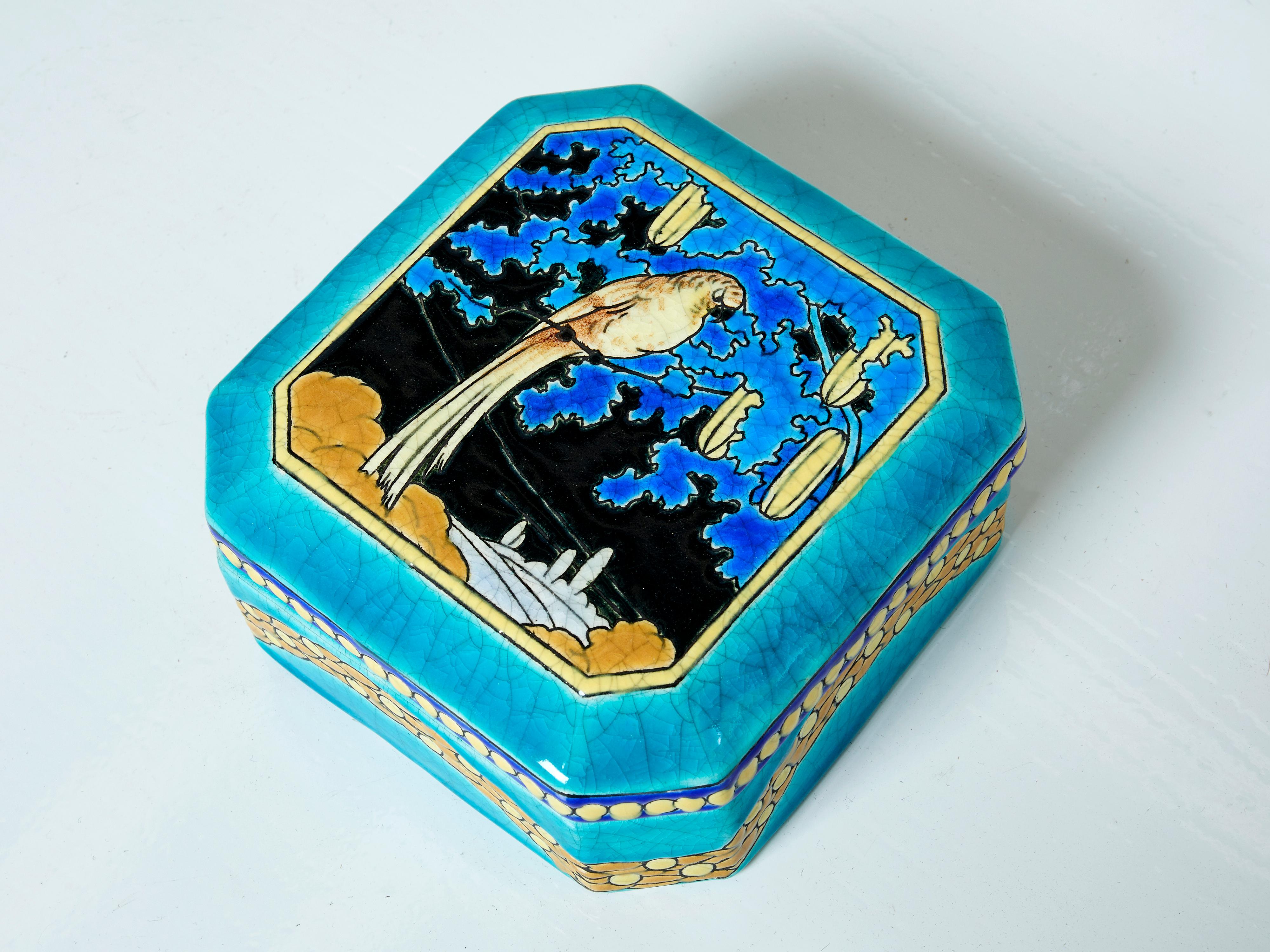Rare grande boîte carrée en céramique Art déco des Faïenceries et Emaux de Longwy réalisée vers 1925. La Chinoiserie cloisonnée émaillée turquoise, lumineuse et audacieuse, représente un magnifique perroquet entouré de feuillage. Le fond bleu