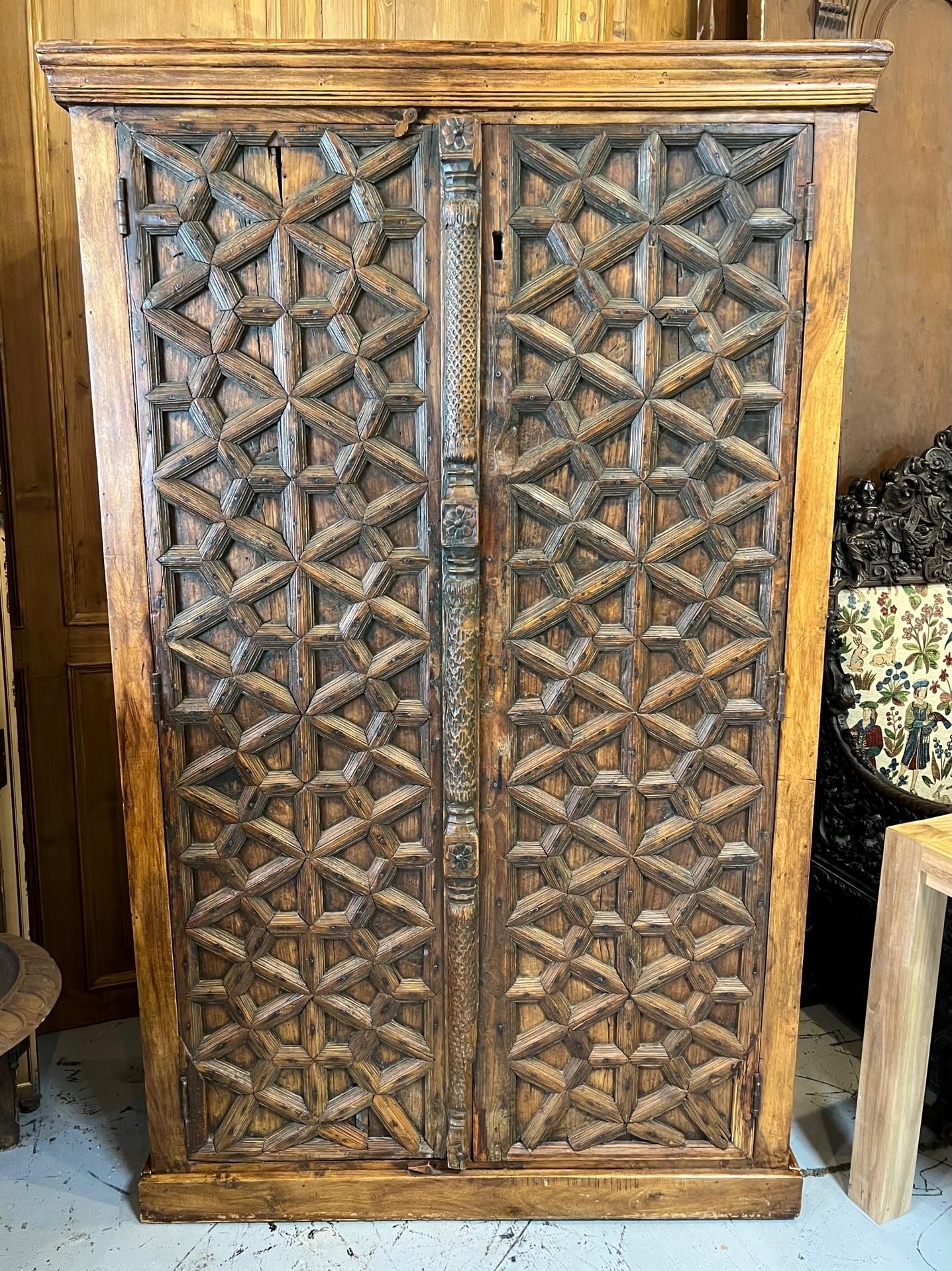 An Indian sheessham wood tall cabinet with antique doors from the late 19th century. The carved doors are just amazing with a beautiful patina that only comes with age. The double doors open with a latch on top and inside are three shelves very