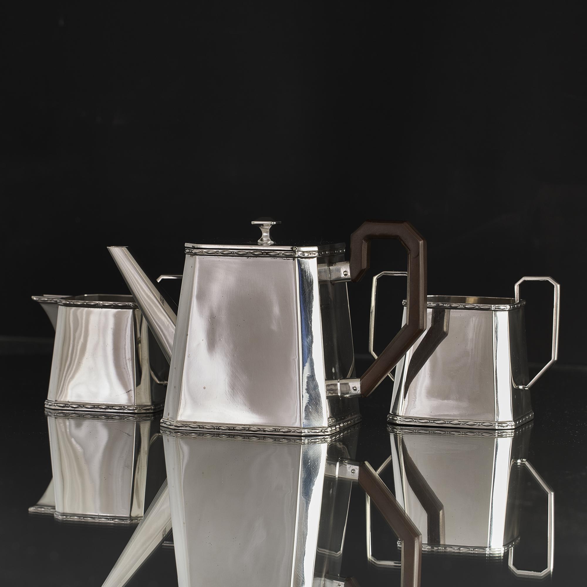 Stylish three-piece Art Deco style silver tea set comprising teapot, milk jug and sugar bowl. The set's trapezoid form and simplicity of style is typical of the Art Deco era with just a discrete ribbon of applied decoration around the top and bottom