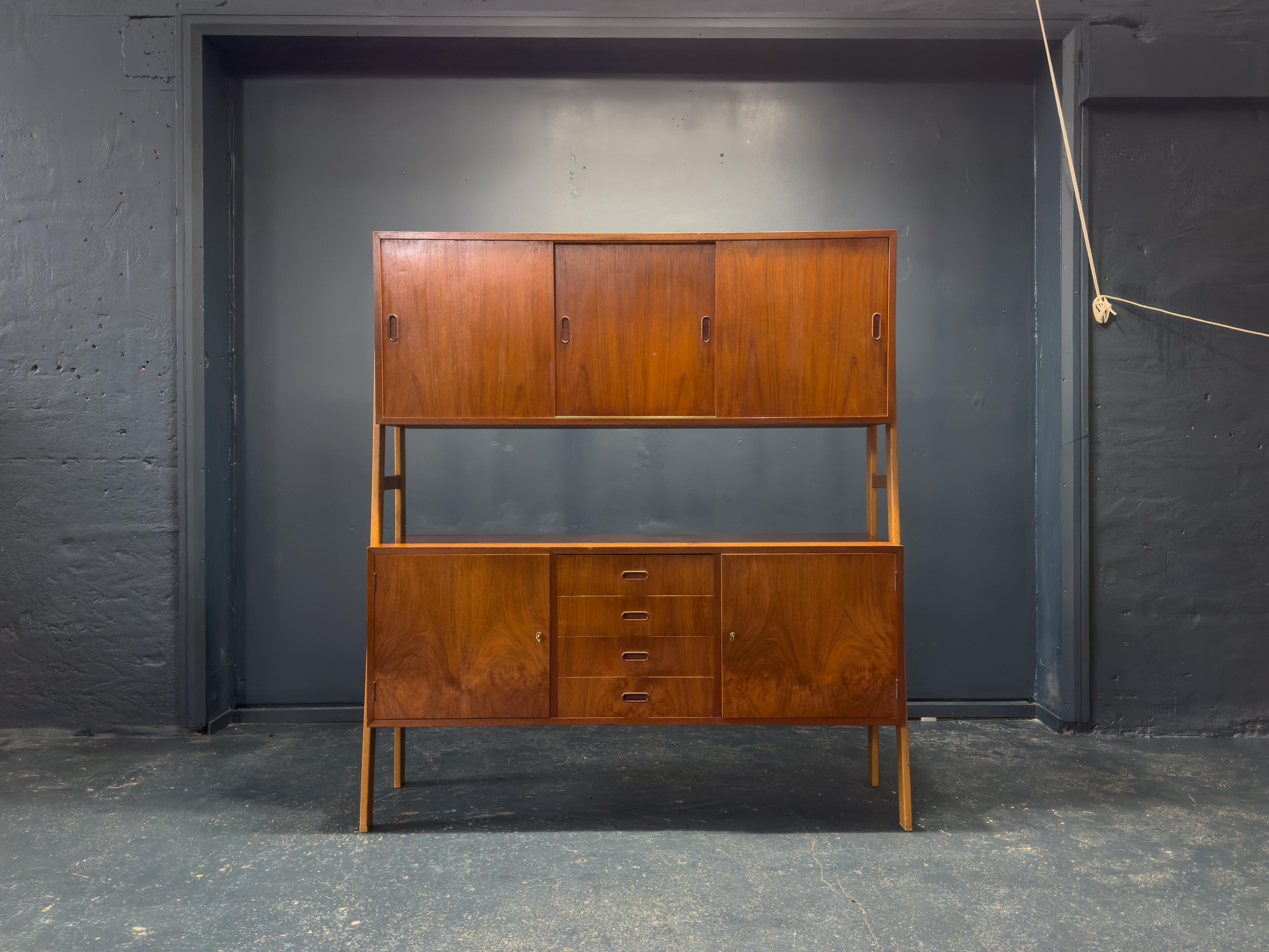Questa squisita credenza in teak della metà del secolo scorso è una straordinaria miscela di eleganza, funzionalità e artigianato. Progettato con una versatile struttura a due livelli, offre un ampio spazio di archiviazione e un'estetica senza tempo