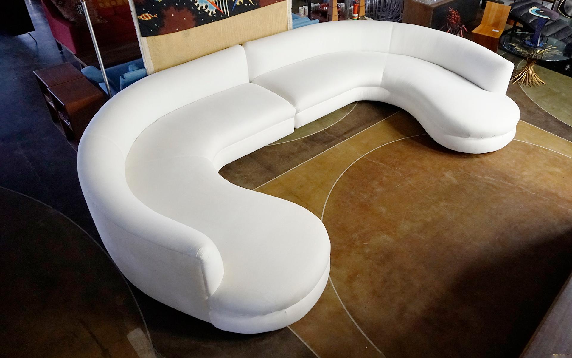 Large two piece curved white cloud sofa in the style of Vladimir Kagan for Directional.  We are unsure of the designer or manufacturer, but the sofa is very high quality construction and in very good condition.  There are areas of yellowing to the