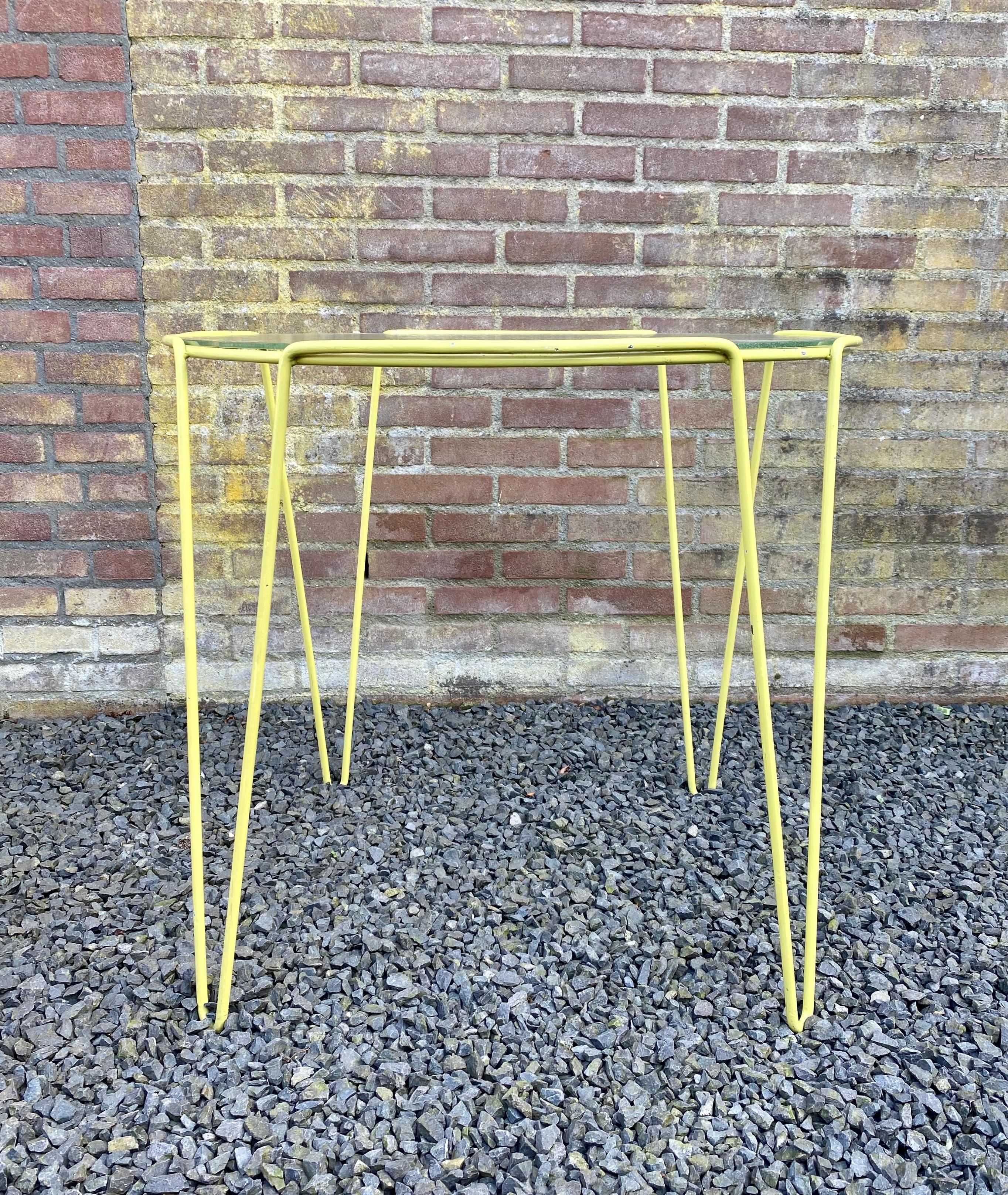 Rara mesa auxiliar de metal lacado amarillo y cristal diseñada por Arnold Bueno de Mesquita para Spurs hacia 1955. De Mesquita fue uno de los iniciadores de la fundación holandesa Goed Wonen en 1946, que promovió la nueva forma de amueblar el hogar.