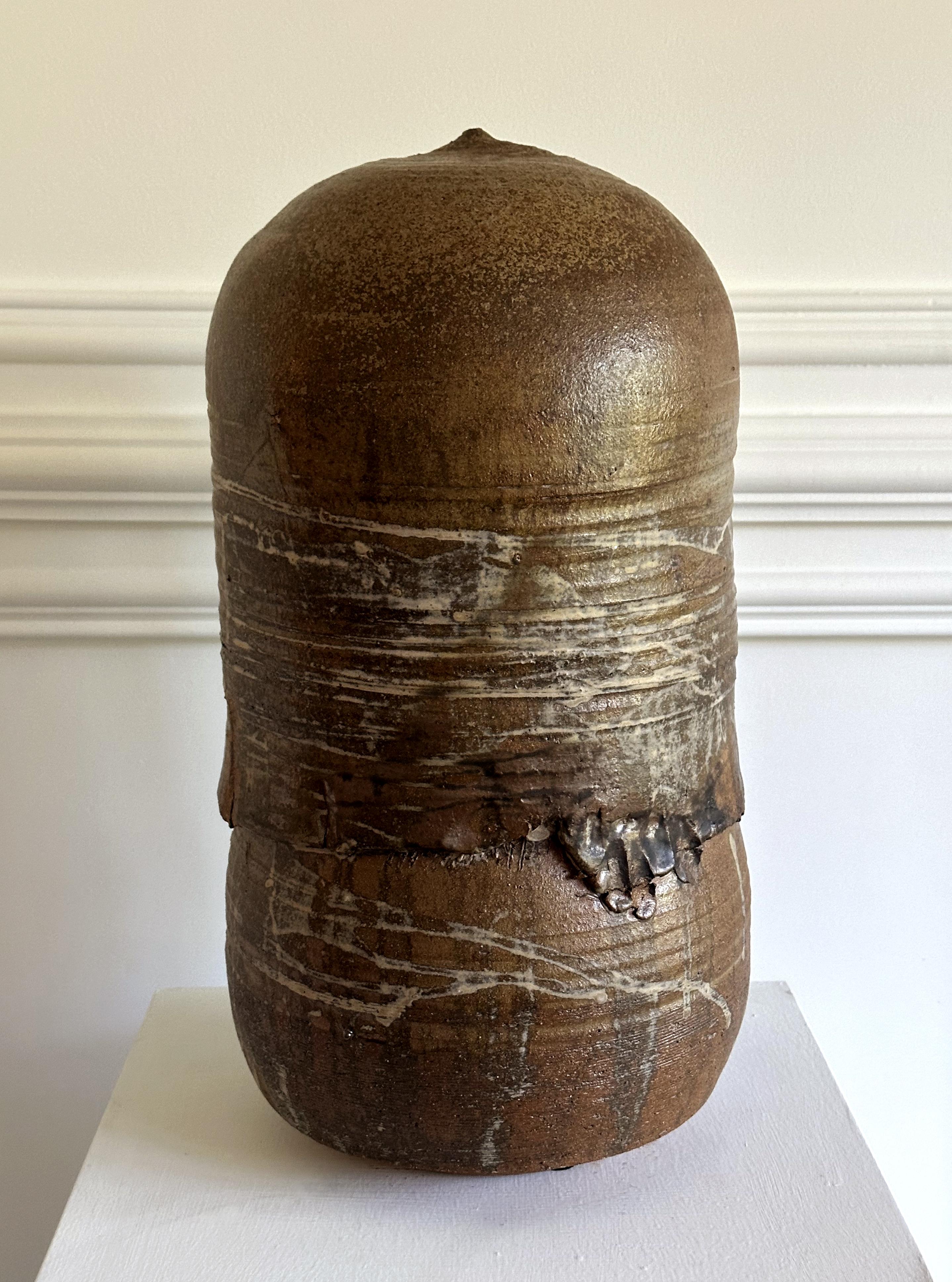 Eine hohe, geschlossene Keramikkanne mit Rassel der japanisch-amerikanischen Künstlerin Toshiko Takaezu (Amerikanerin, 1922 - 2011) aus den 1980-90er Jahren. Das eindrucksvolle Steingefäß ist mit einer dunkelbraunen Glasur überzogen, die einen