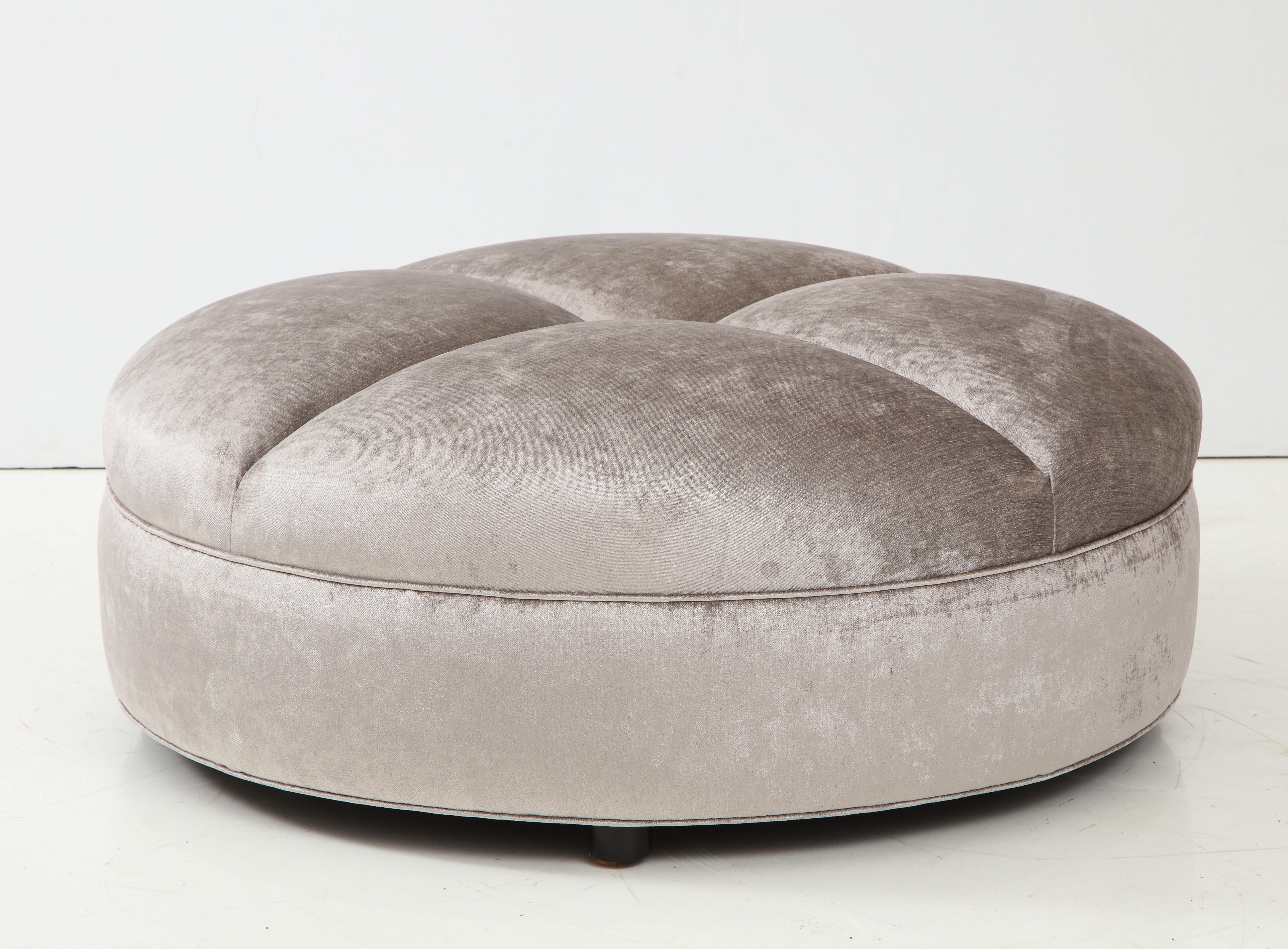The oversized ottoman has been beautifully reupholstered in a luxurious silvery grey velvet fabric and sits up on four barrel shaped feet.