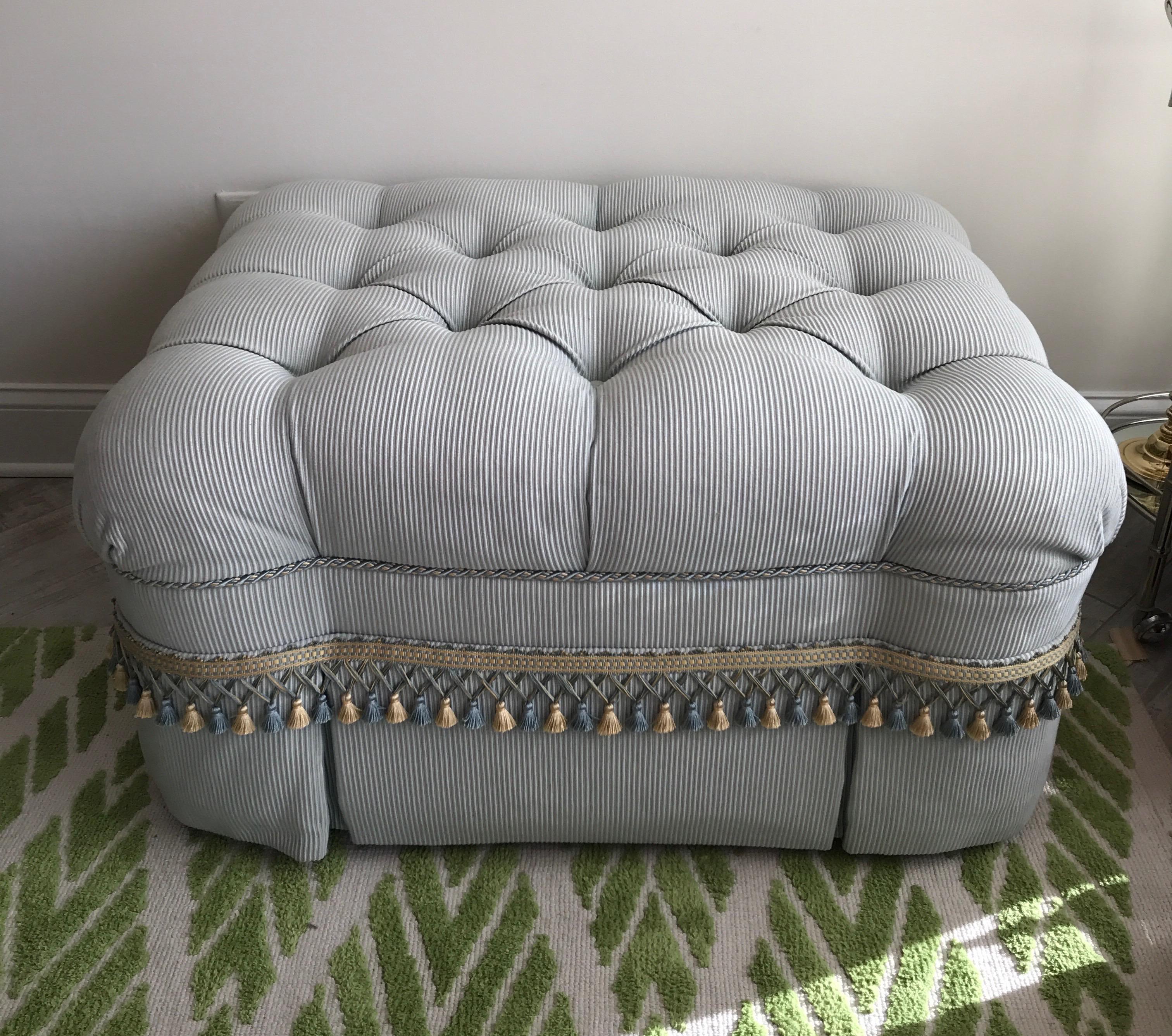 Large tufted ottoman in a light blue ticking with cream & blue fringe.