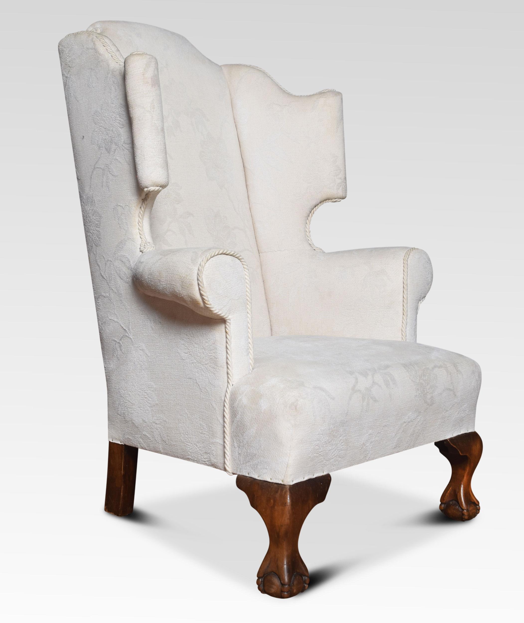 Oversized mahogany framed wing armchair of generous proportions, the shaped top above upholstered back, arms and seat ( the fabric is serviceable but has some marks). All raised up on squat cabriole front legs terminating in ball and claw