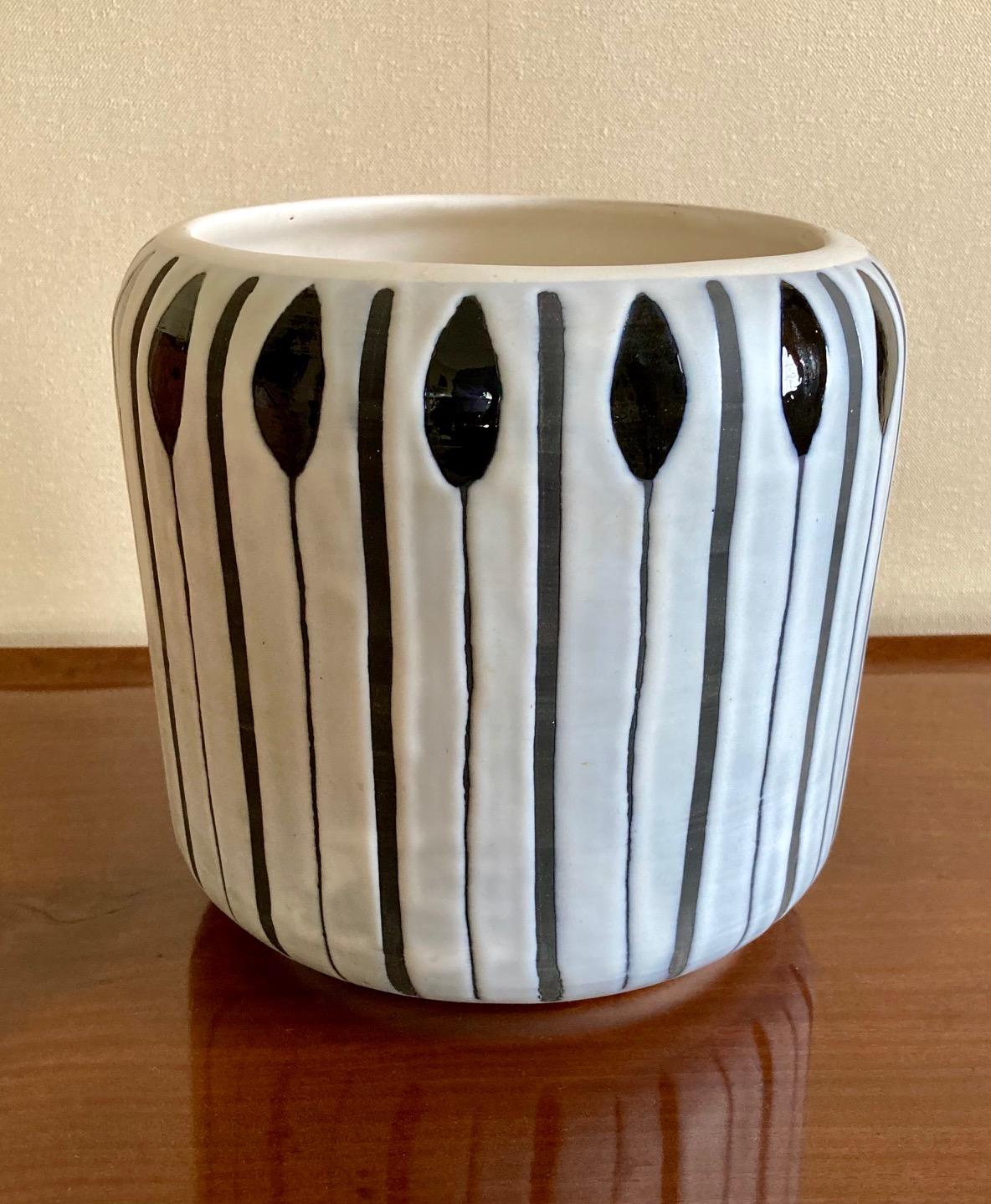A large cylindrical vase, cachepot or wine cooler,
White glazed ceramic with blue and black decoration.
Stamped underneath: Capron Vallauris France
Vallauris, France, circa 1960.

Measures : 
Height 21.5 cm (8.5 in.)
Diameter 22.5 cm (8.9