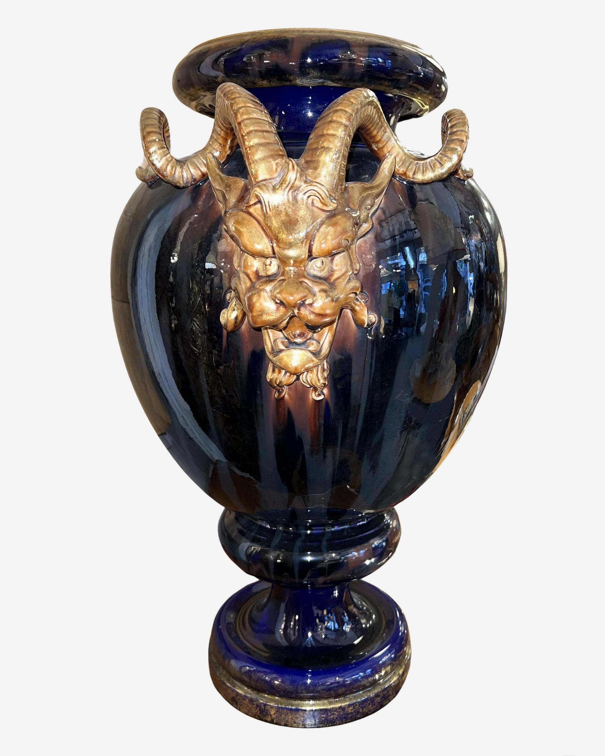 Grande vaso su piedistallo, decorato con teste di fauni, in terracotta smaltata di Sarreguemines.
Ricoperte di smalto blu cobalto fiammato, le impugnature a forma di testa di fauno sono dorate in oro, così come il collo del vaso e il fondo del